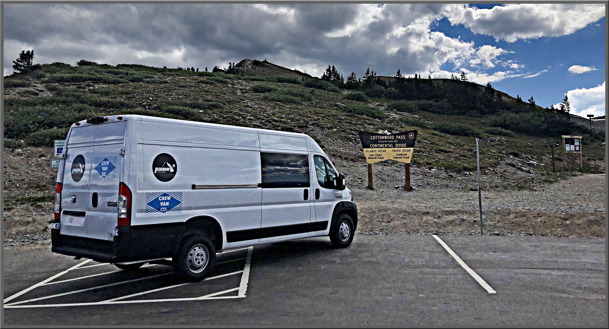 Cycling Cottonwood Pass, Tayler Camp, Colorado - white PJAMM Cycling SAG van parked in parking lot next to NPS sign for Cottonwood Pass, Continental Divide