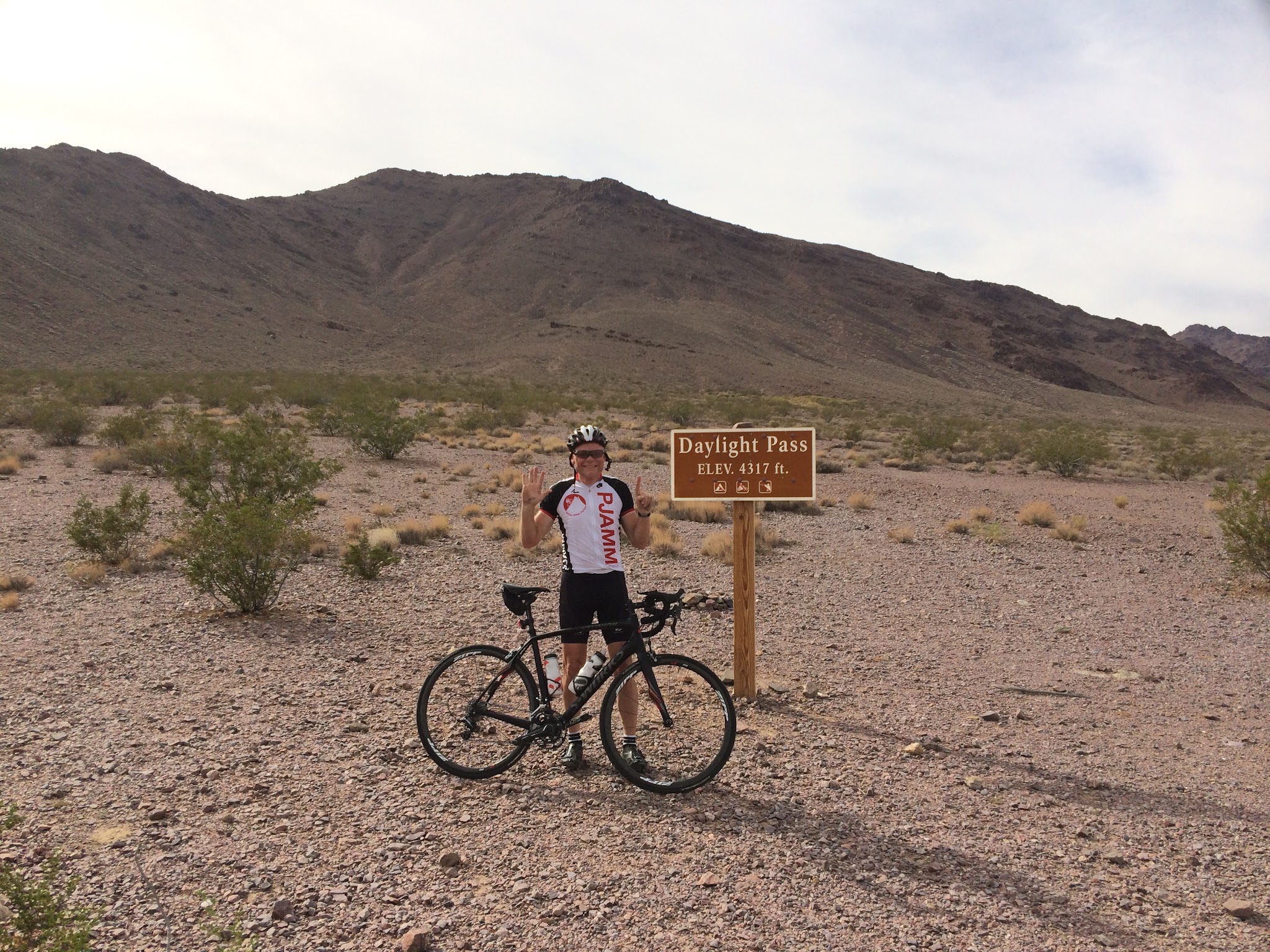 Cycling Daylight Pass Death Valley - cyclist at pass sign with bike