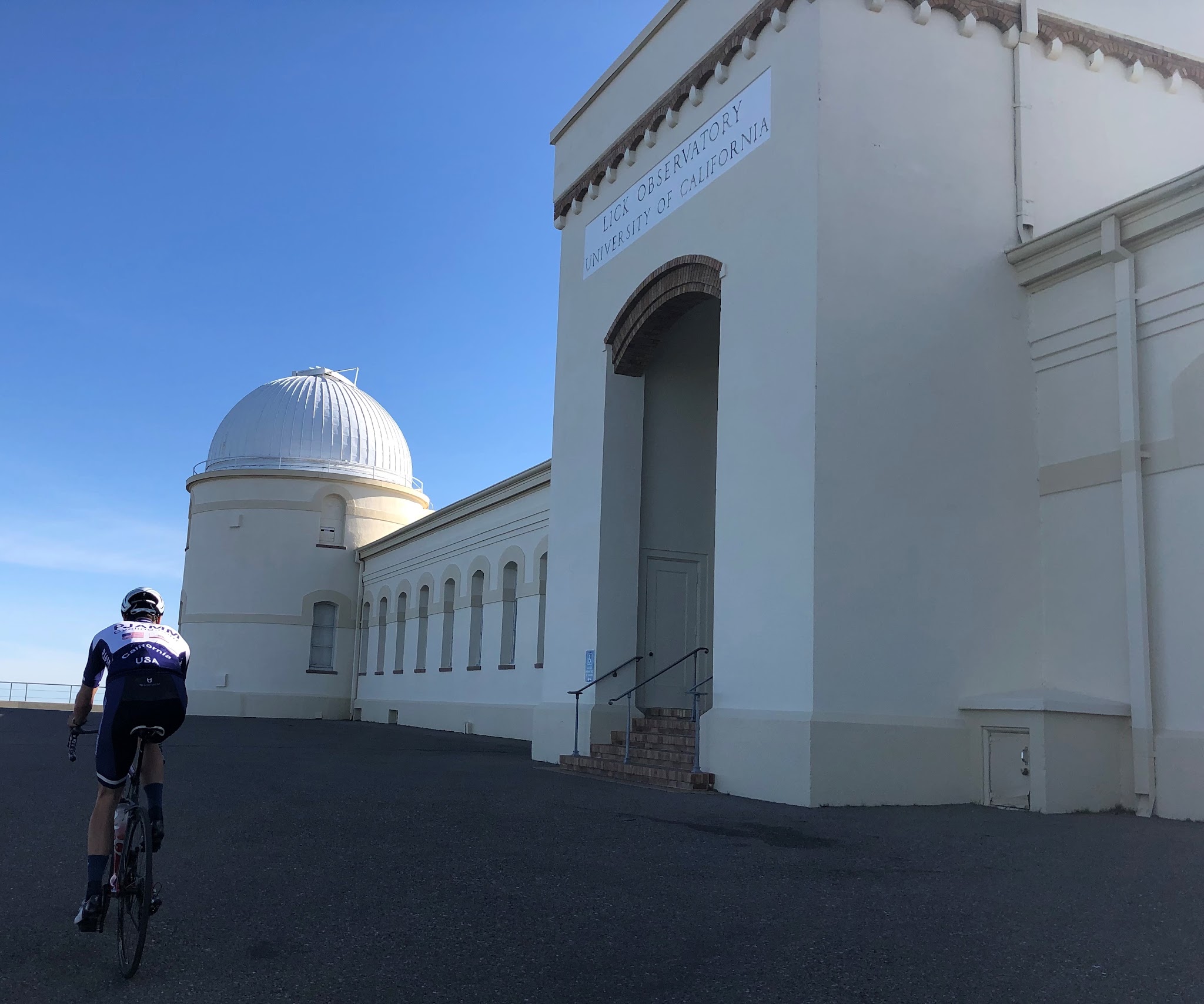 Biking Mt. Hamilton West - Lick Observatory entrance. Cyclist riding past front of Lick Observatory.