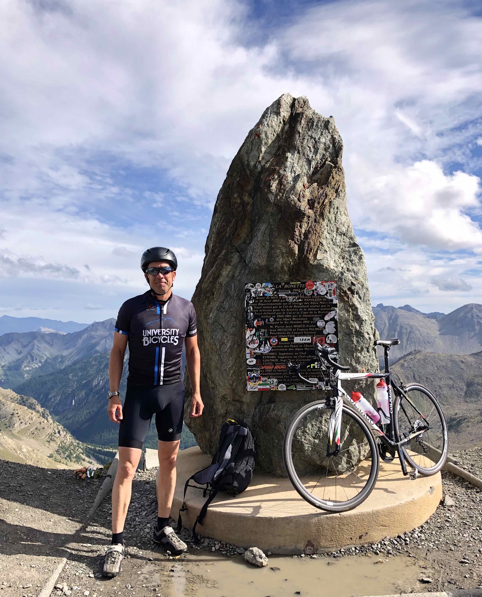 Cycling Cime Bonette from Jausiers, France - PJAMM Cyclist Ard Oostra stands next to monument on climb summit