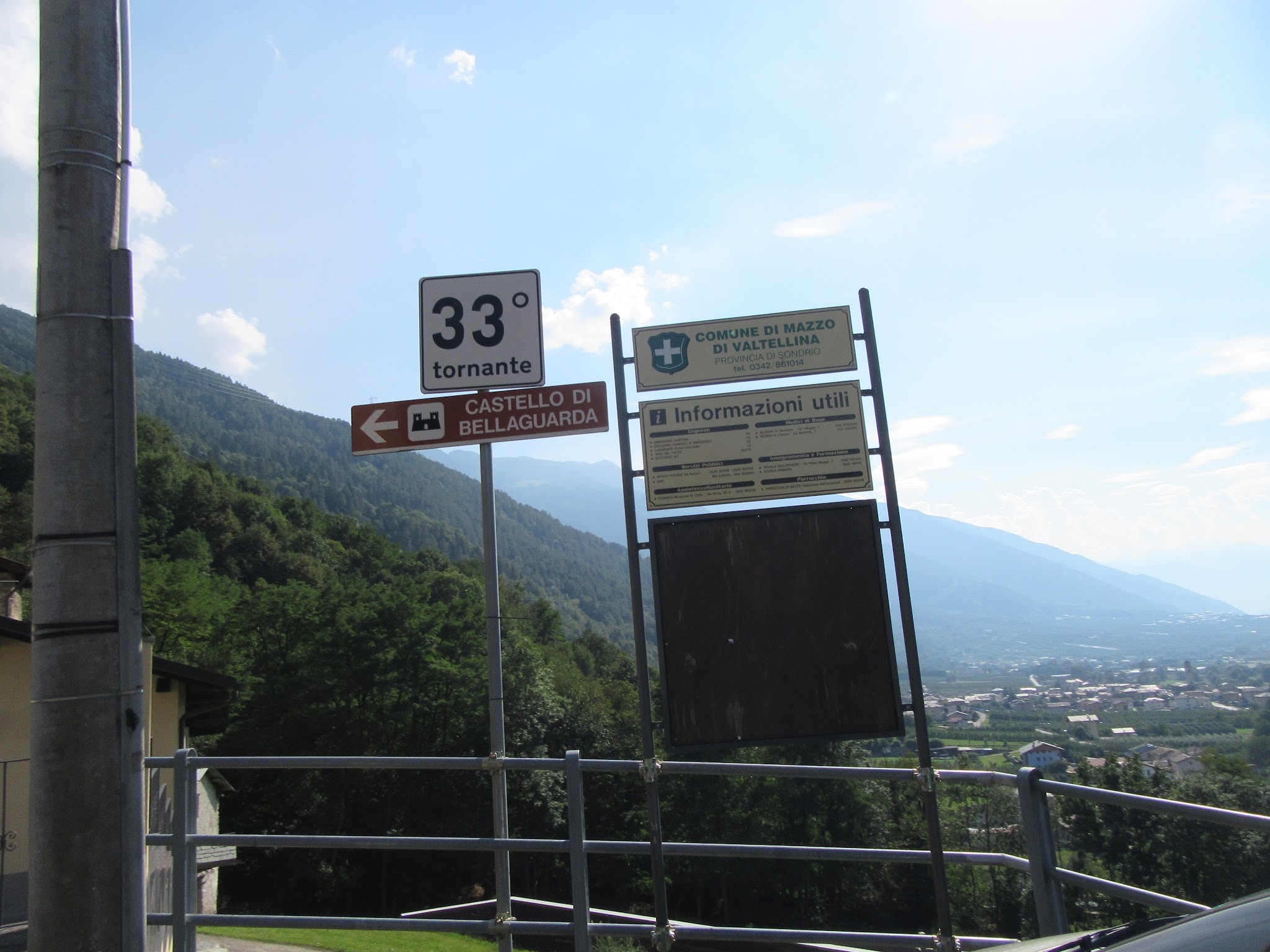 cycling Passo del Mortirolo from Mazzo di Valtellina - Tornanti (hairpin) #33 sign with town in background
