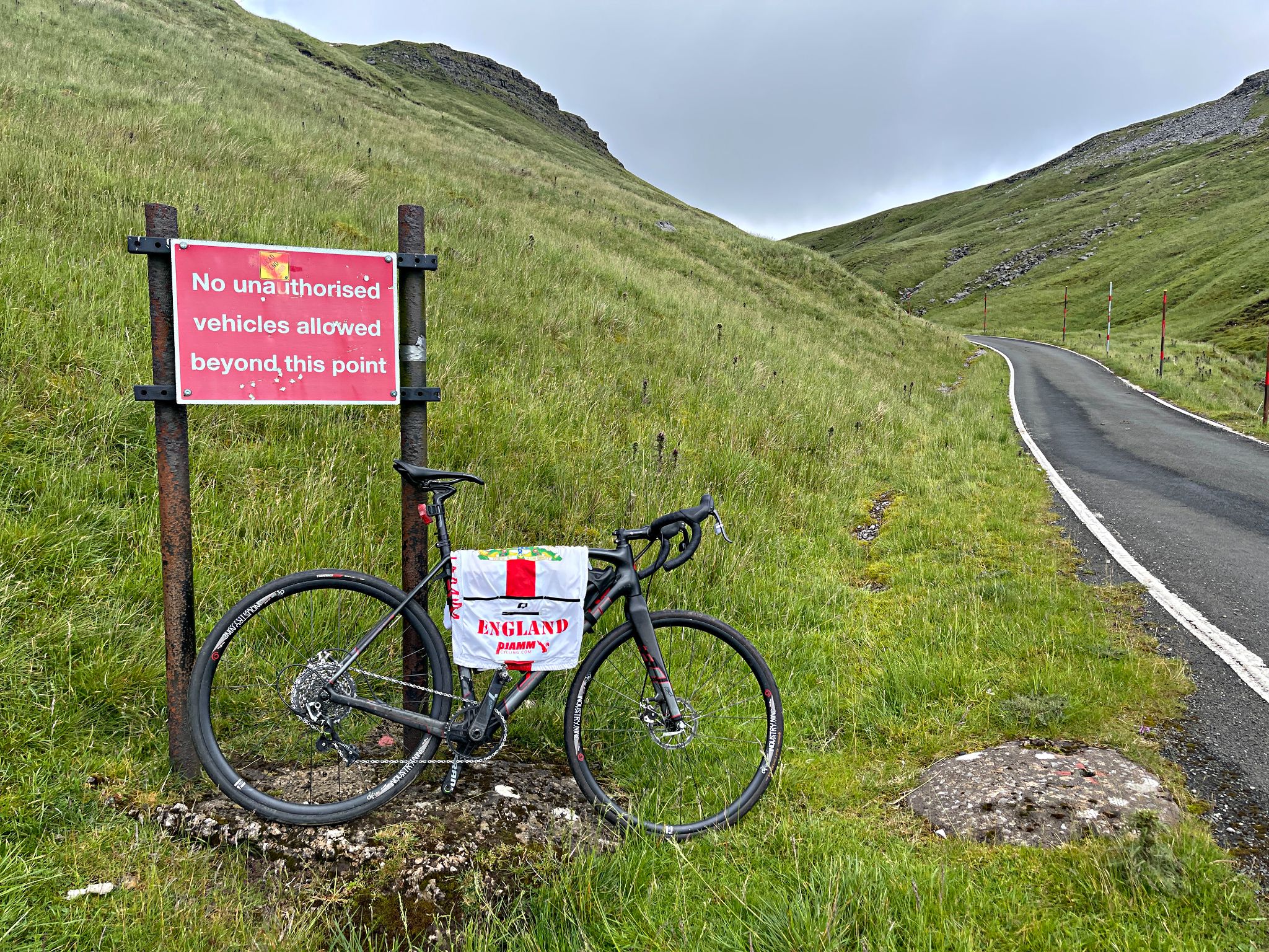 bike parked next to sign warning "no unauthorized vehicles allowed beyond this point"