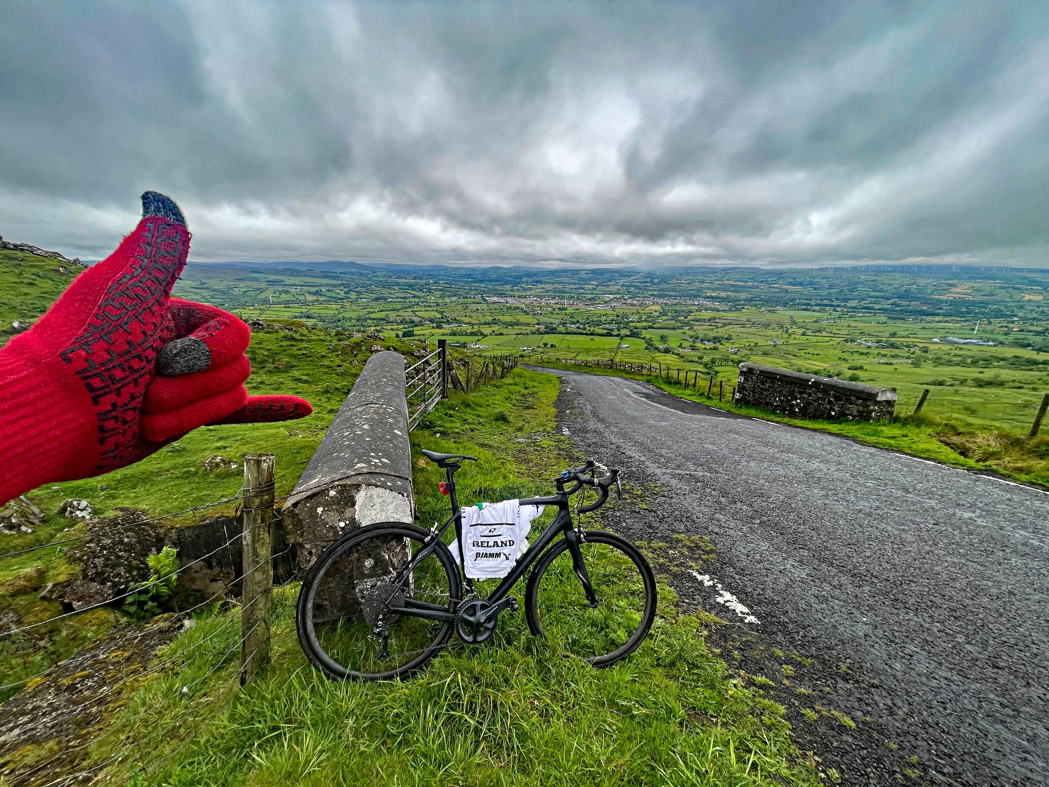 bike parked in green grass on hillside looking down over the 17% grade of the steepest 500 meter segment of the climb