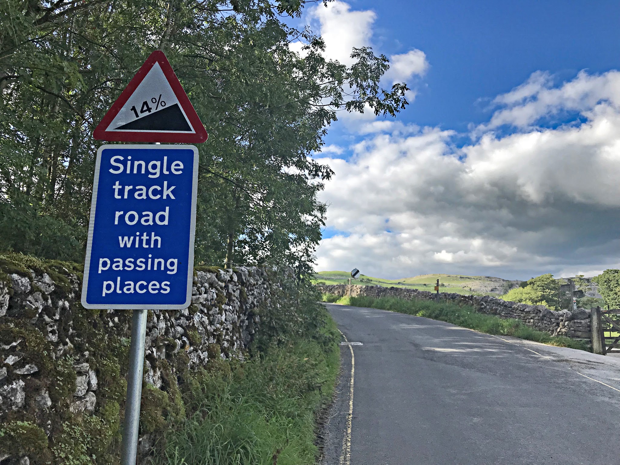 Cycling Malham Cove - 14% grade road sign warning "Single track road with passing places", along one-lane road with low rock fence along side