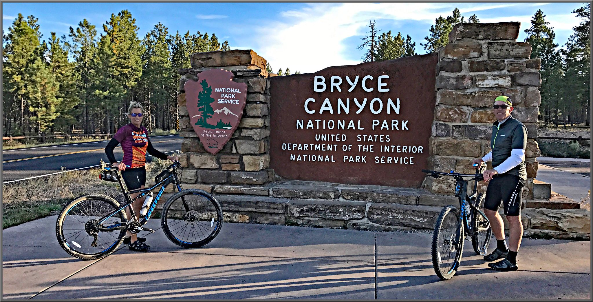 Cycling Bryce Canyon National Park, Utah - two PJAMM Cyclists stand in front of NPS sign for Bryce Canyon National Park
