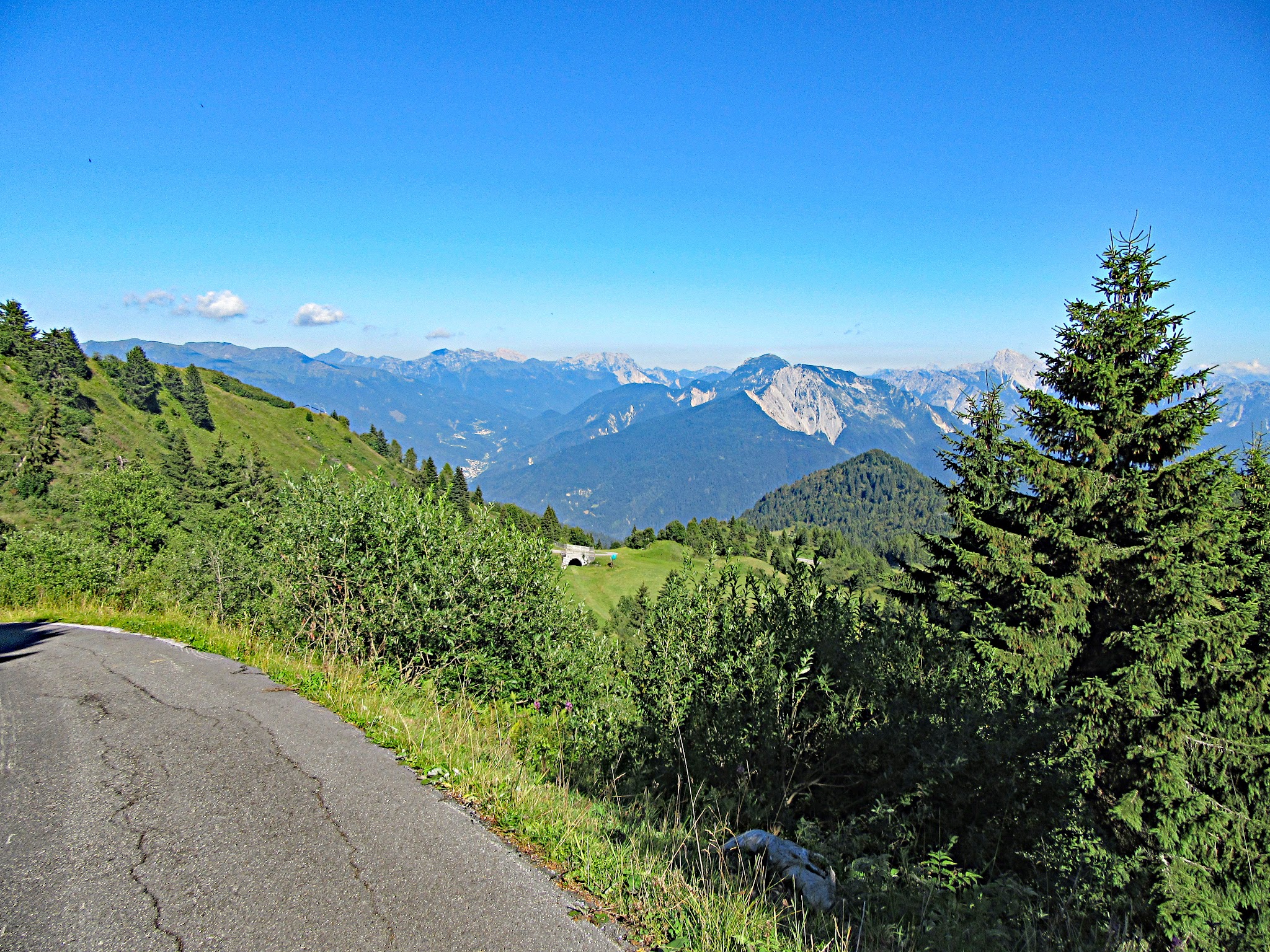 Climbing by bike Cycling Monte Zoncolan from Priola - road with mountains, sky and clouds in background.