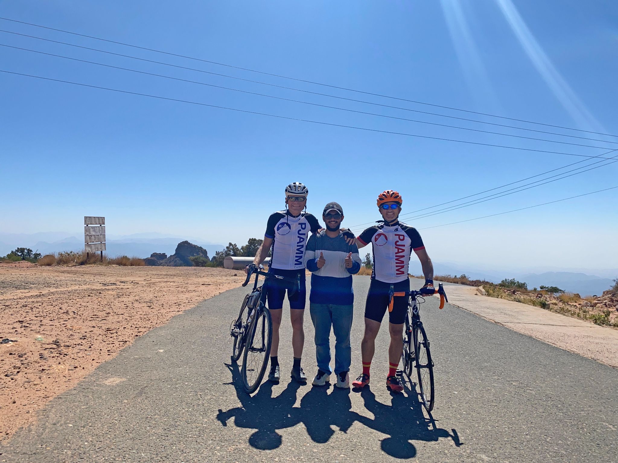 Cycling Rdom Pass, Asir Mountains - PJAMM Cyclists stand with guide at the top of the Rdom Pass climb, Forest Al Ymani, Saudi Arabia
