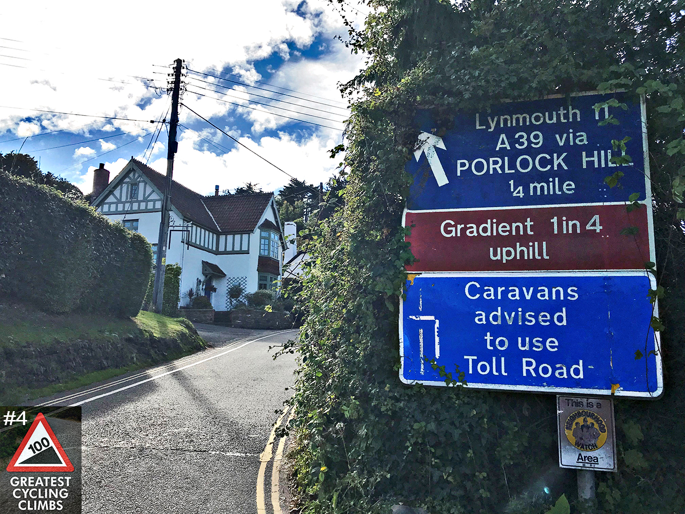 Cycling Porlock Hill, England - road signs warning of Gradient Uphill, Caravans advised to use toll road, road winding around corner, large white home on side of road, Simon Warren's 100 Greatest Cycling Climbs #4 logo in corner
