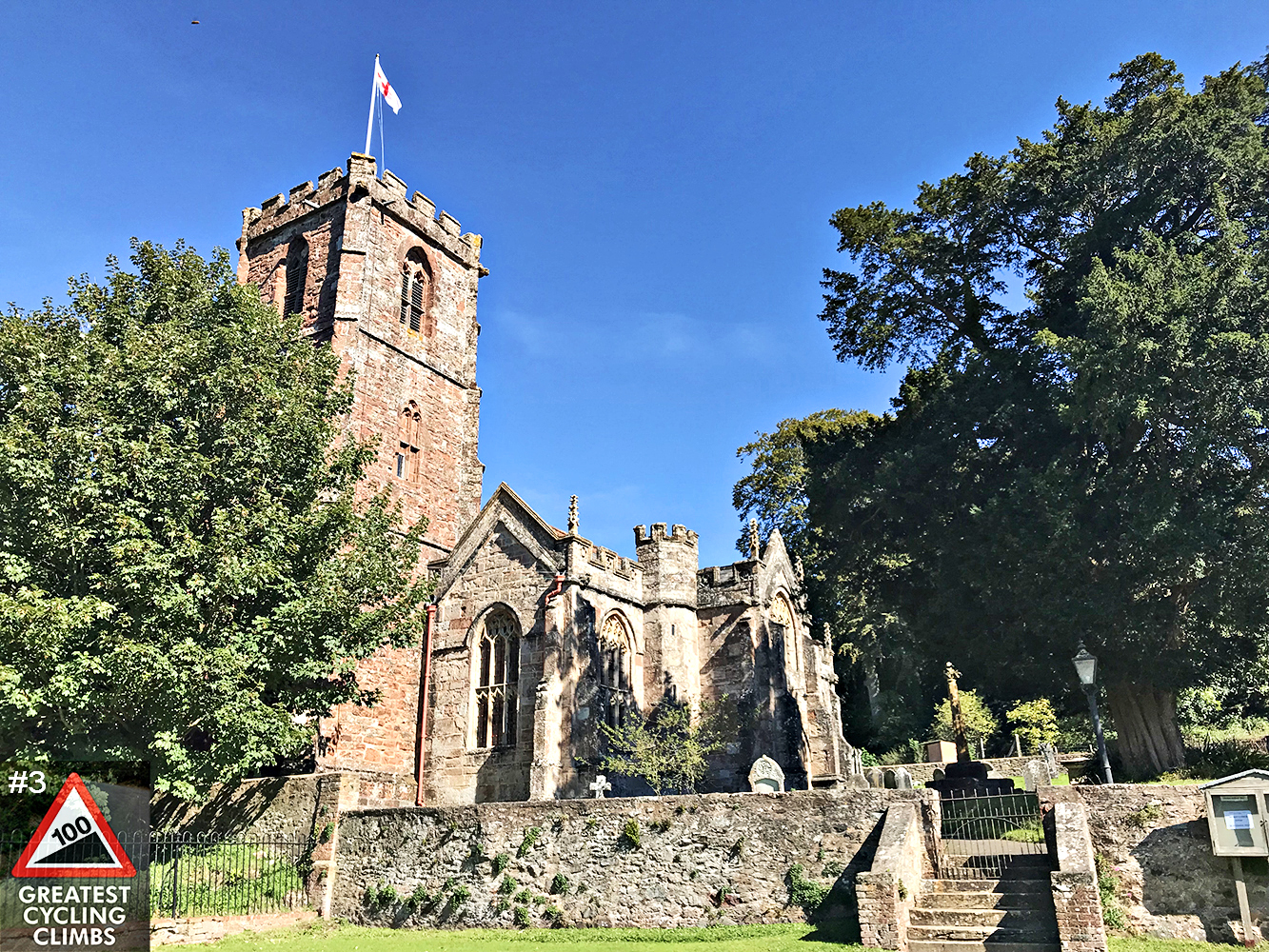 Climbing Crowcombe Comb, Somerset - Church of the Holy Ghost, old, gothic looking church made of brick, Simon Warren's 100 Greatest Cycling Climbs #3 logo in corner