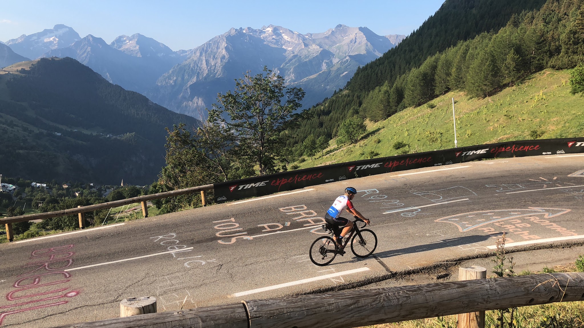 Cycling Alpe d'Huez - cyclist riding bike over road with tour de france road paint, mountains in background