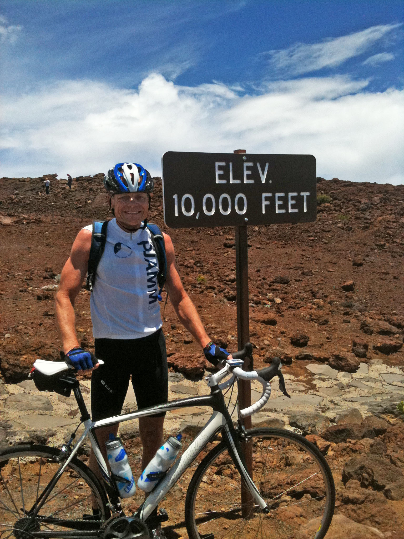 Climbing Haleakala Volcano  by bike - John Johnson with bike at 10,000' sign