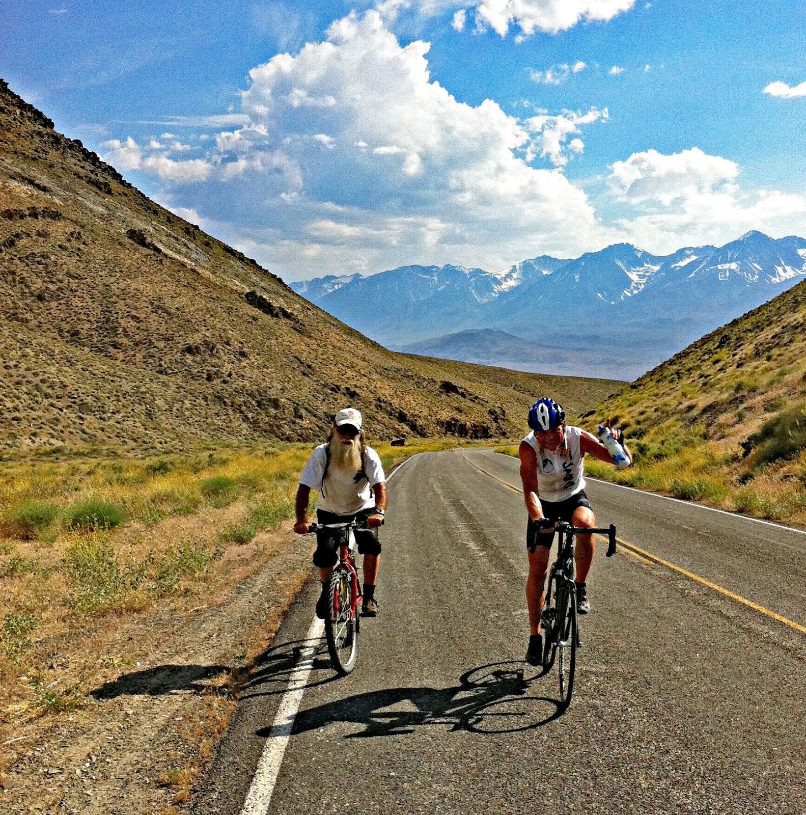 Cycling white mountain with road, cyclists and sierras in background