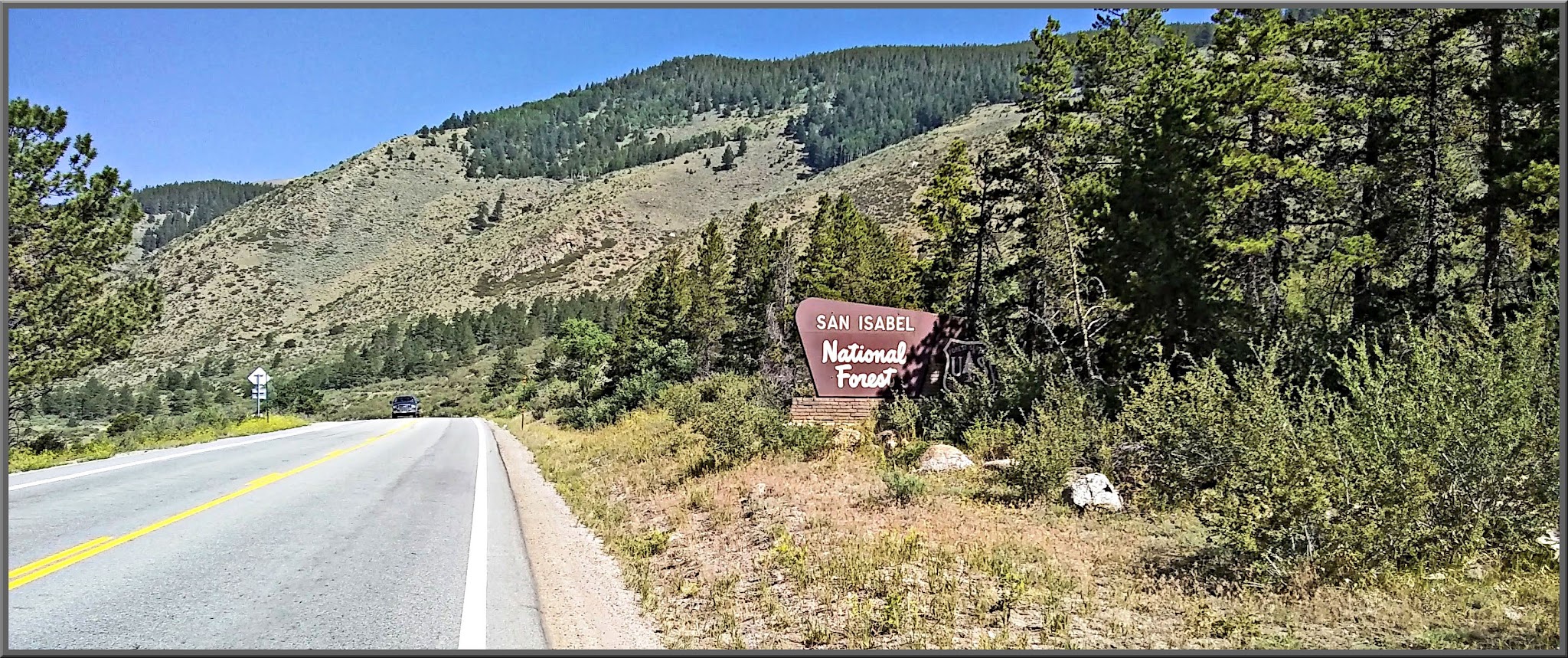 Cycling Monarch Pass East, Colorado - NPS Sign for San Isabel National Forest, forested hillsides along two-lane roadway