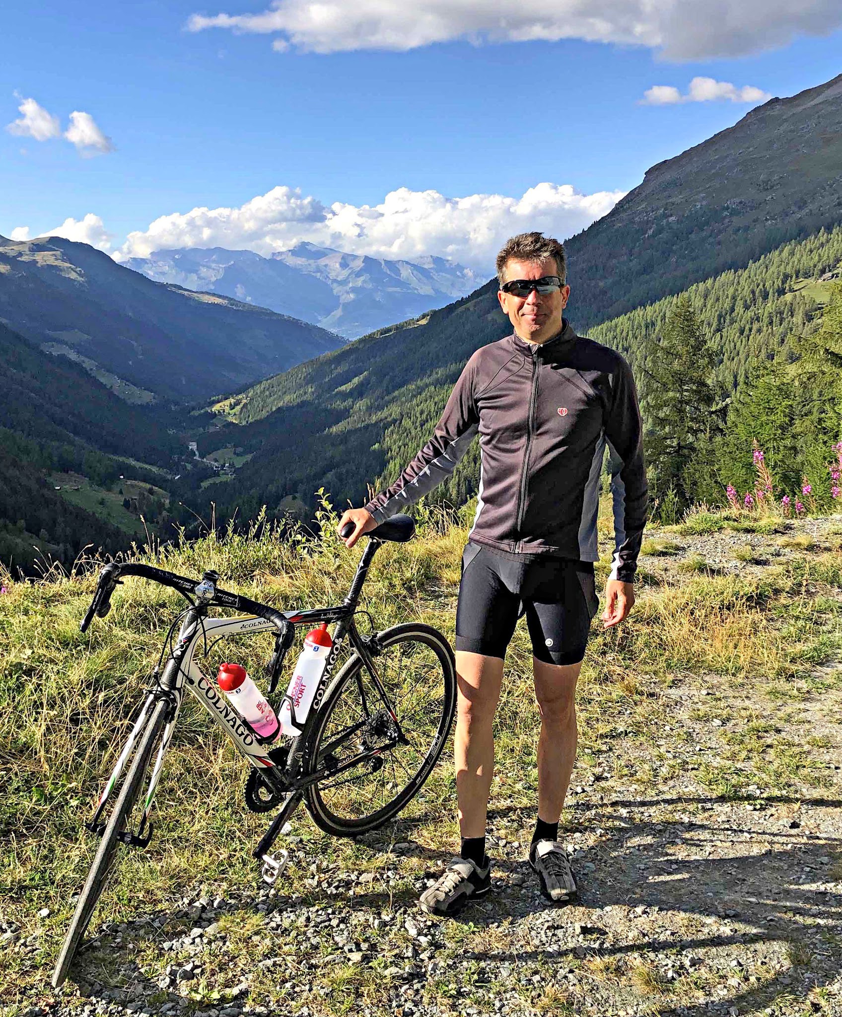 Cycling Barrage de la Grande Dixence, Switzerland Cycling Barrage de la Grande Dixence, Switzerland - PJAMM Cyclist Ard Oostra stands with his bike on roadside, swiss alps in background