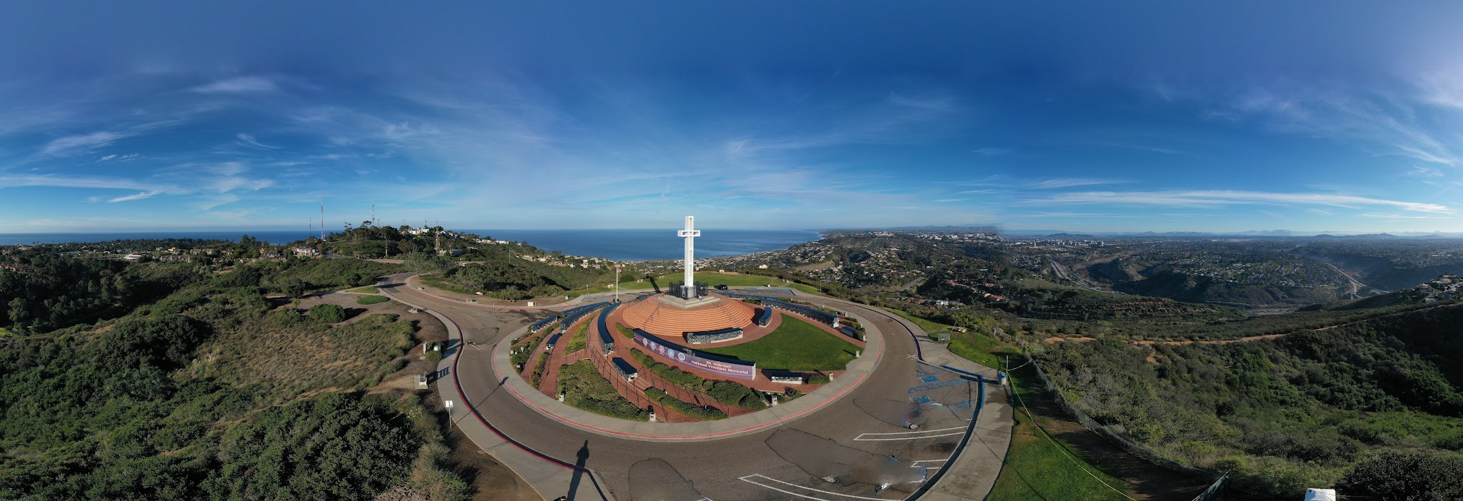 aerial drone view shows panoramic view of Veteran's Memorial atop Mt. Soledad, with Pacific Ocean in the background