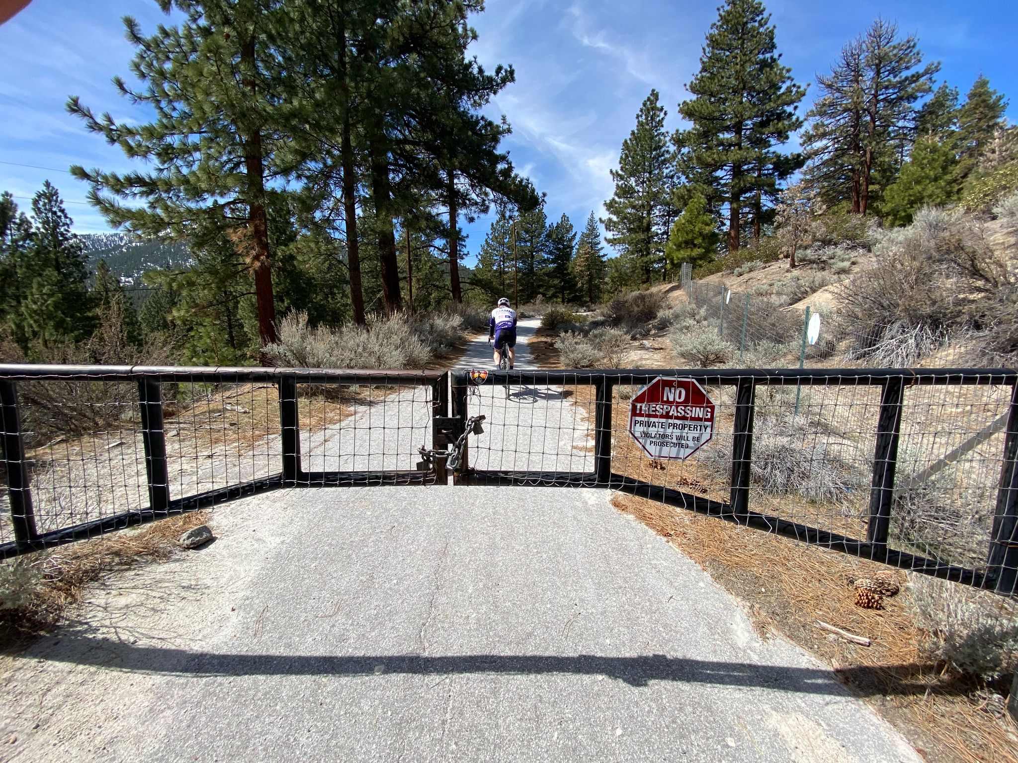 Cycling Old Clear Creek Road, NV - PJAMM Cyclist rides bike on road beyond closed gate