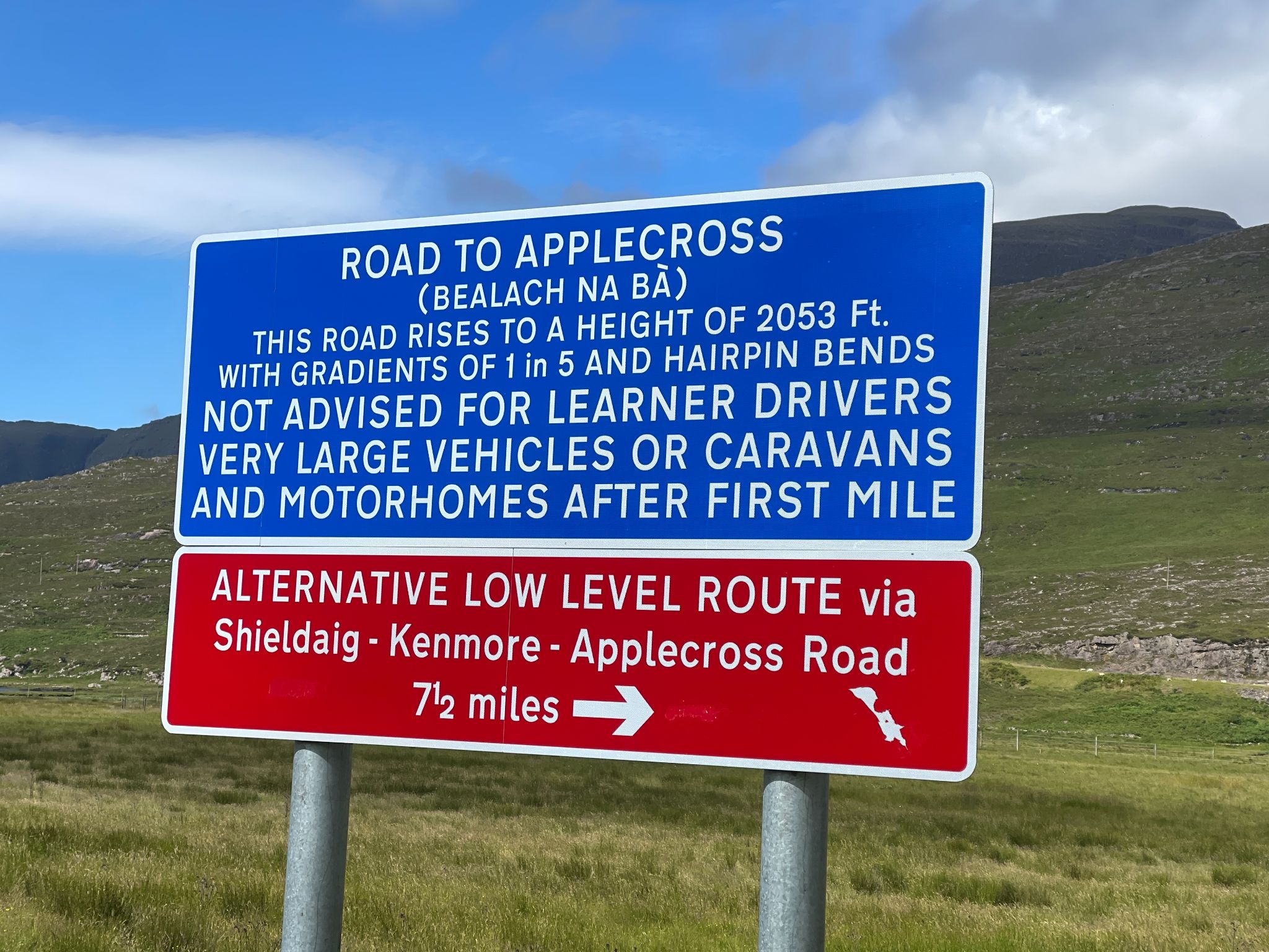 blue and red street sign warns that the road is not advised for learner drivers, large vehicles, and motorhomes.