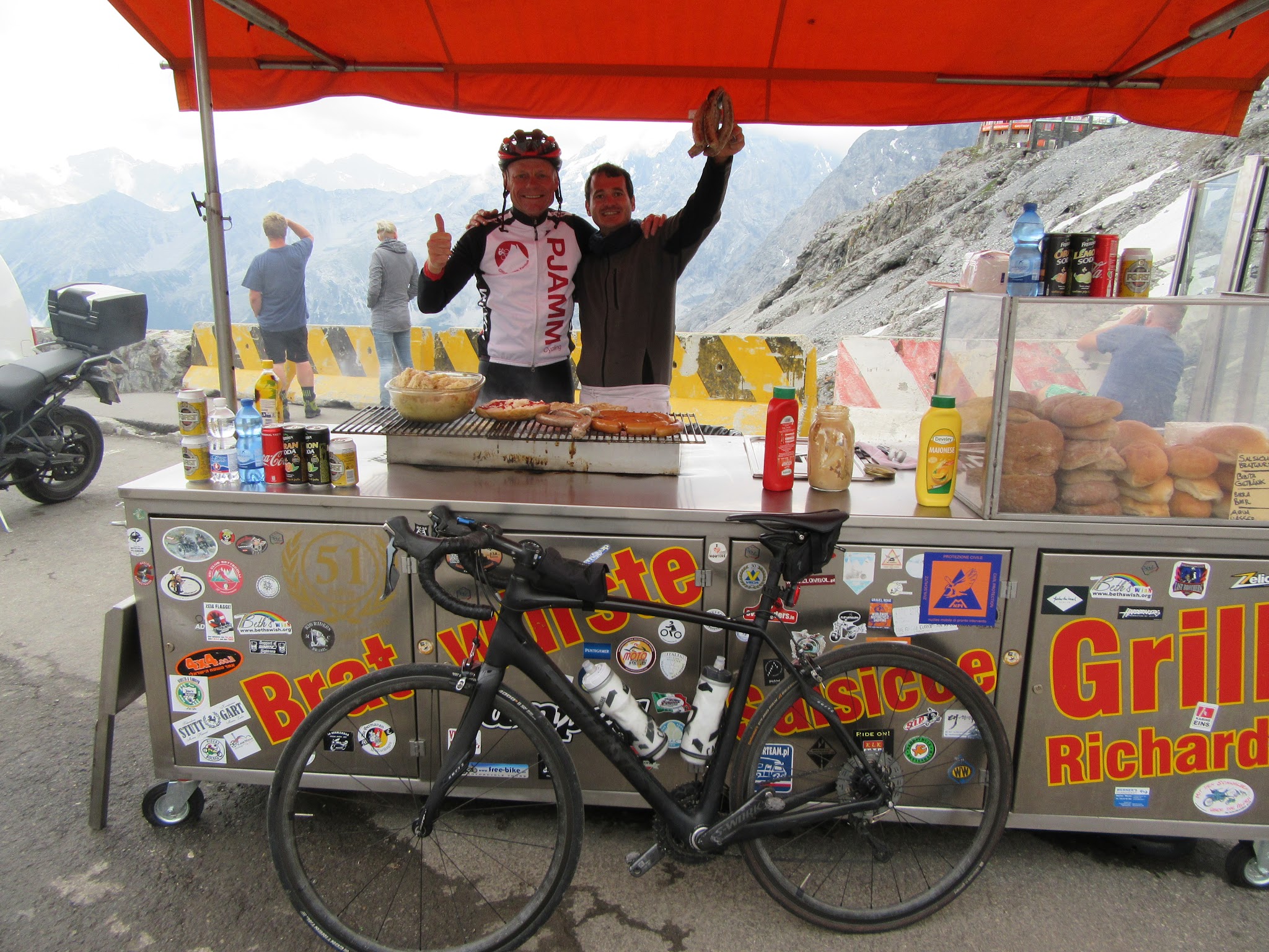 Umbrail Pass bike climb - bratwurst and food cart at passo dello stelvio with cyclist, bike and cook