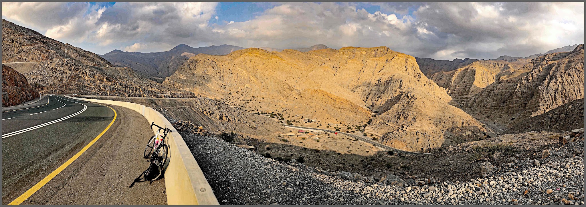 Jebel Jais, Ras Al Khaimah, UAE Jebel Jais, Ras Al Khaimah, UAE - bike parked on shoulder of highway against cement retaining wall, desert mountain landscape