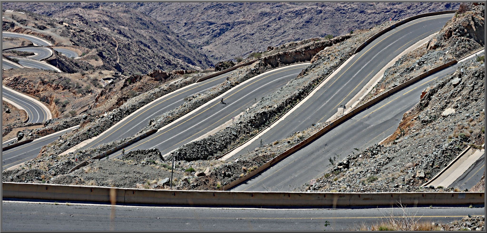 Cycling Bashout Pass, Saudi Arabia - view looking down on roadway from above, road snakes sharply back and forth with many hairpins up the mountainside
