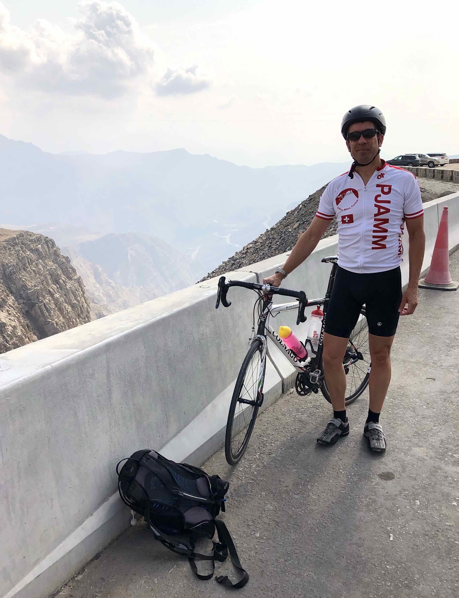 Jebel Jais, Ras Al Khaimah, UAE Jebel Jais, Ras Al Khaimah, UAE - PJAMM Cyclist stands with bike near retaining wall on mountainside