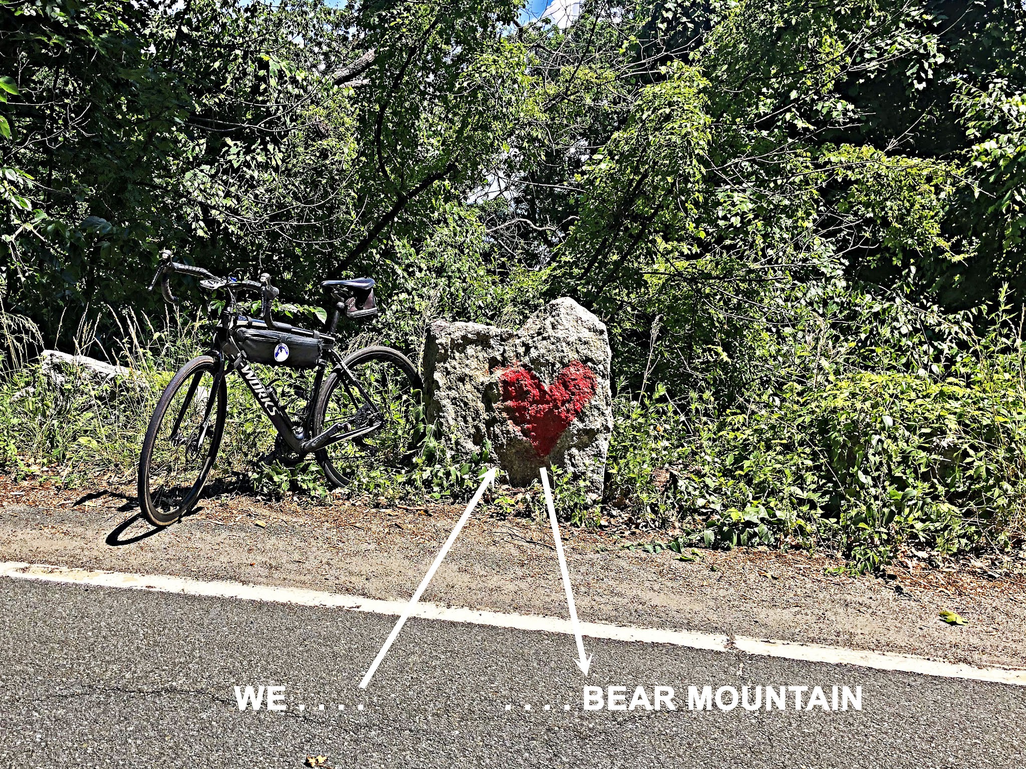 Cycling Bear Mountain, New York - bike parked next to large grey rock with red heart painted on it on roadside