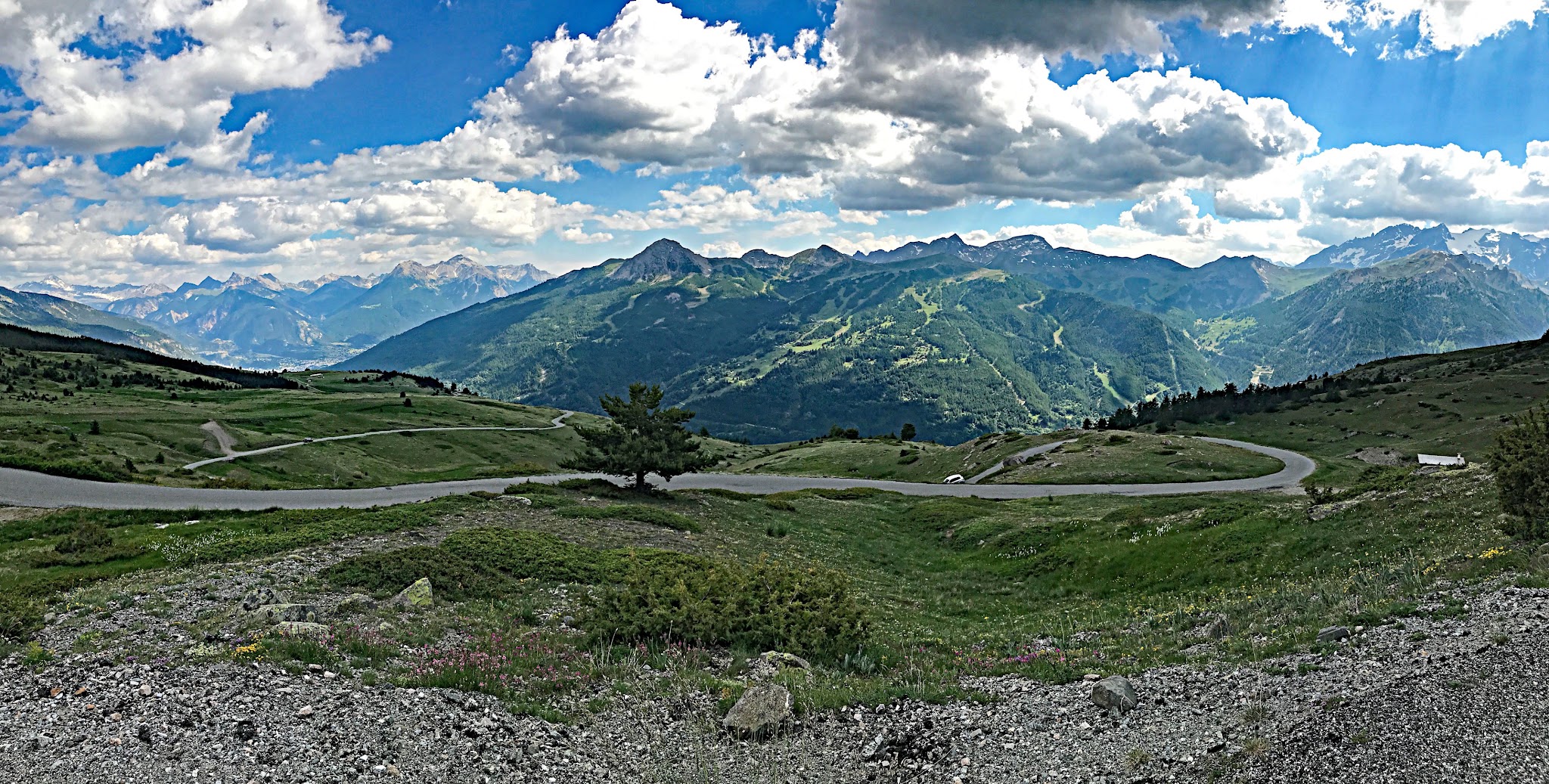 Cycling Col du Granon - panoramic view of switchback early in the climb; sharp mountain range in distance