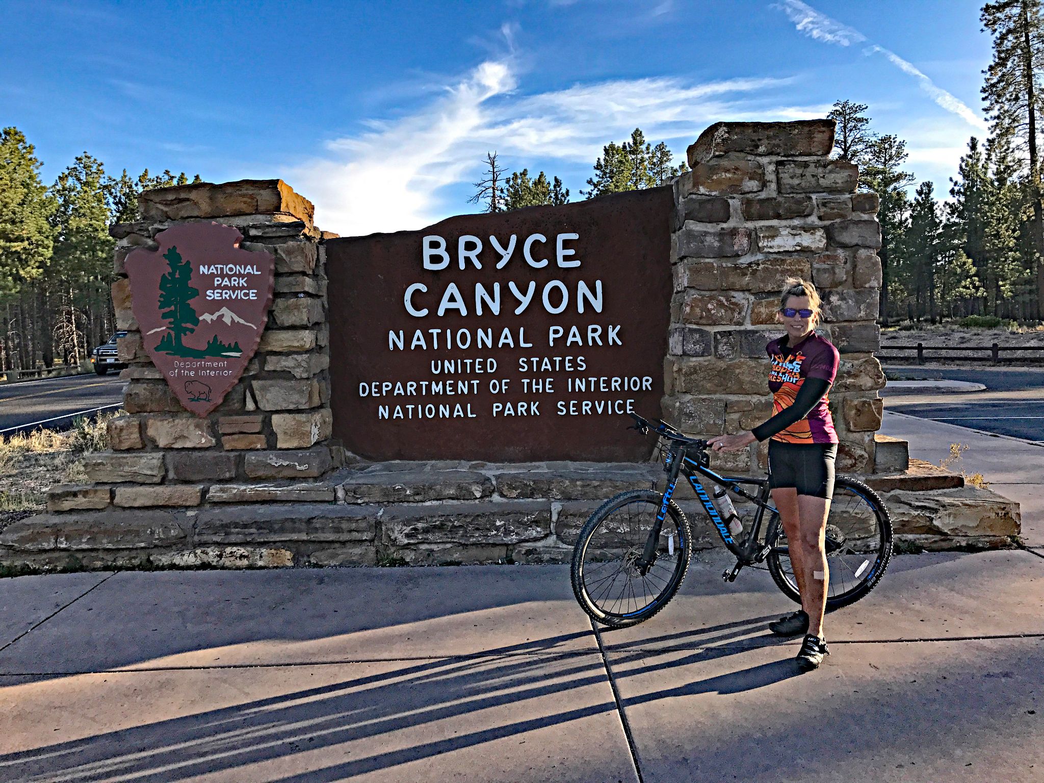 Cycling Bryce Canyon National Park, Utah - PJAMM Cyclists stands in front of NPS sign for Bryce Canyon National Park