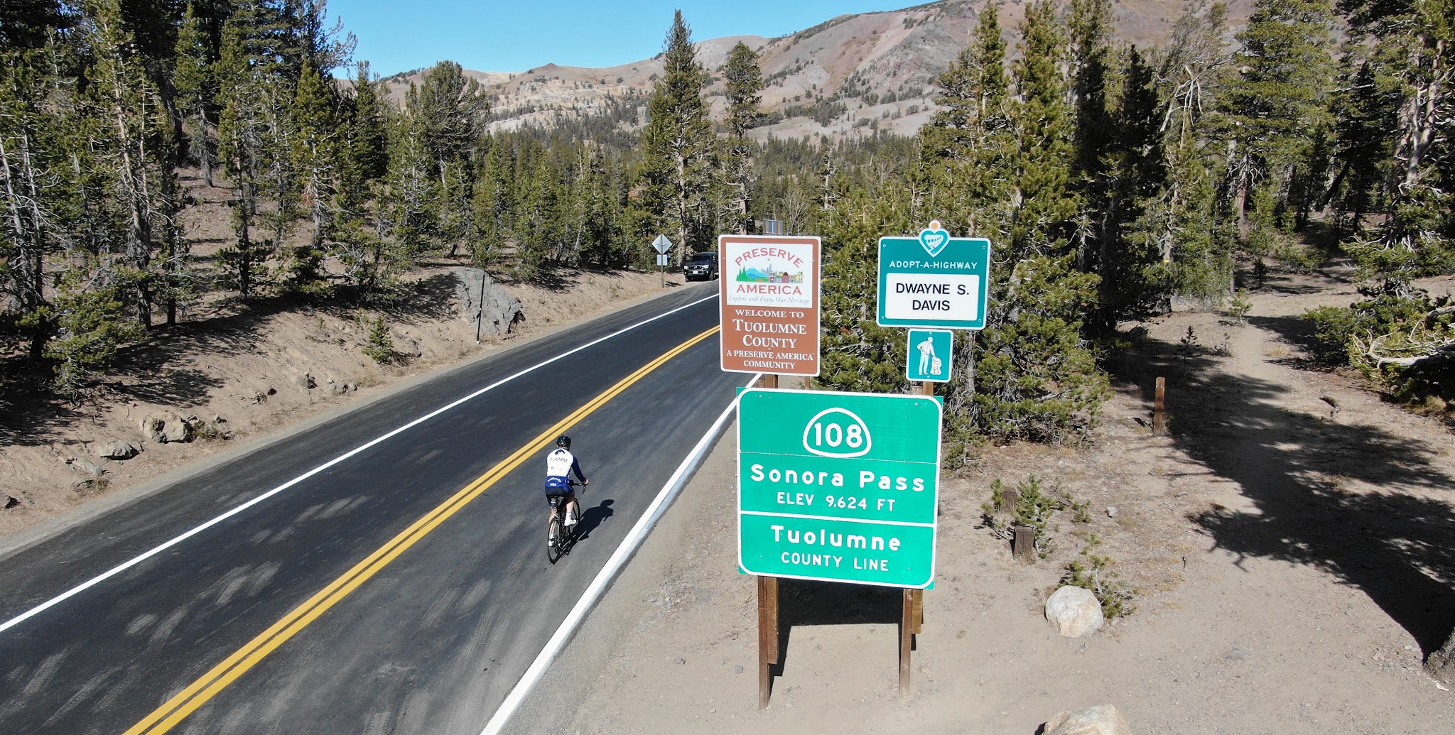 Cycling Sonora Pass West - steep grade sign and roadway surrounded by forest