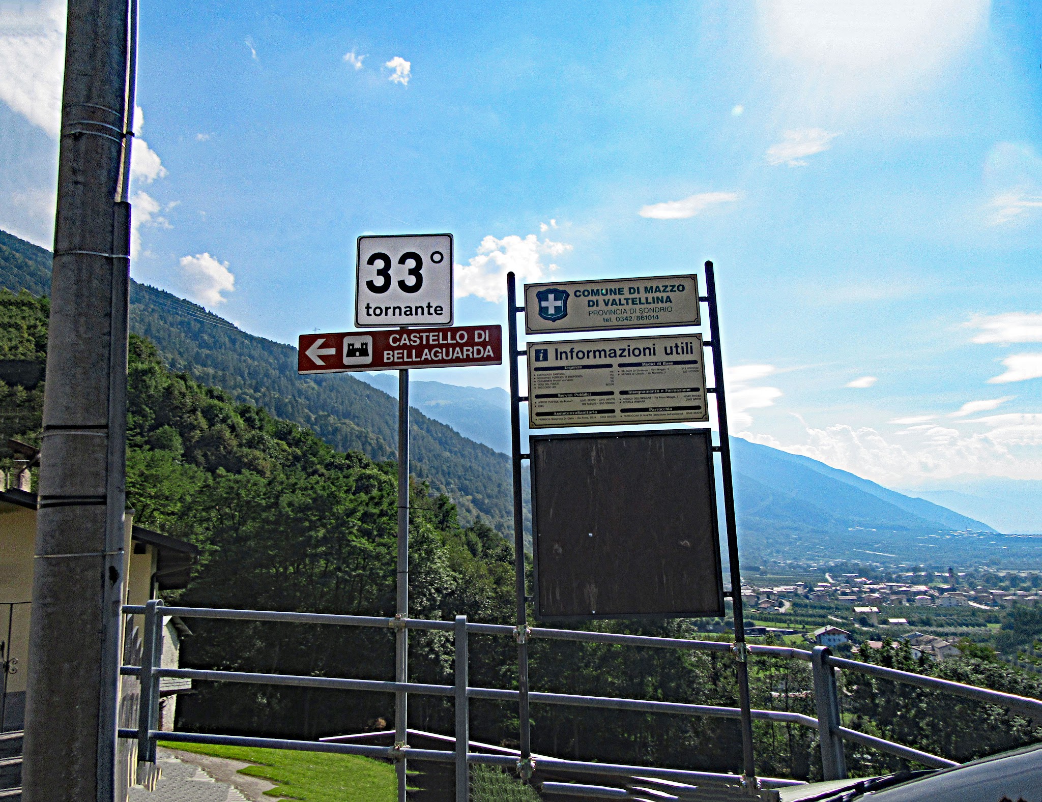 cycling Passo del Mortirolo from Mazzo di Valtellina - Tornanti (hairpin) #33 sign with town in background