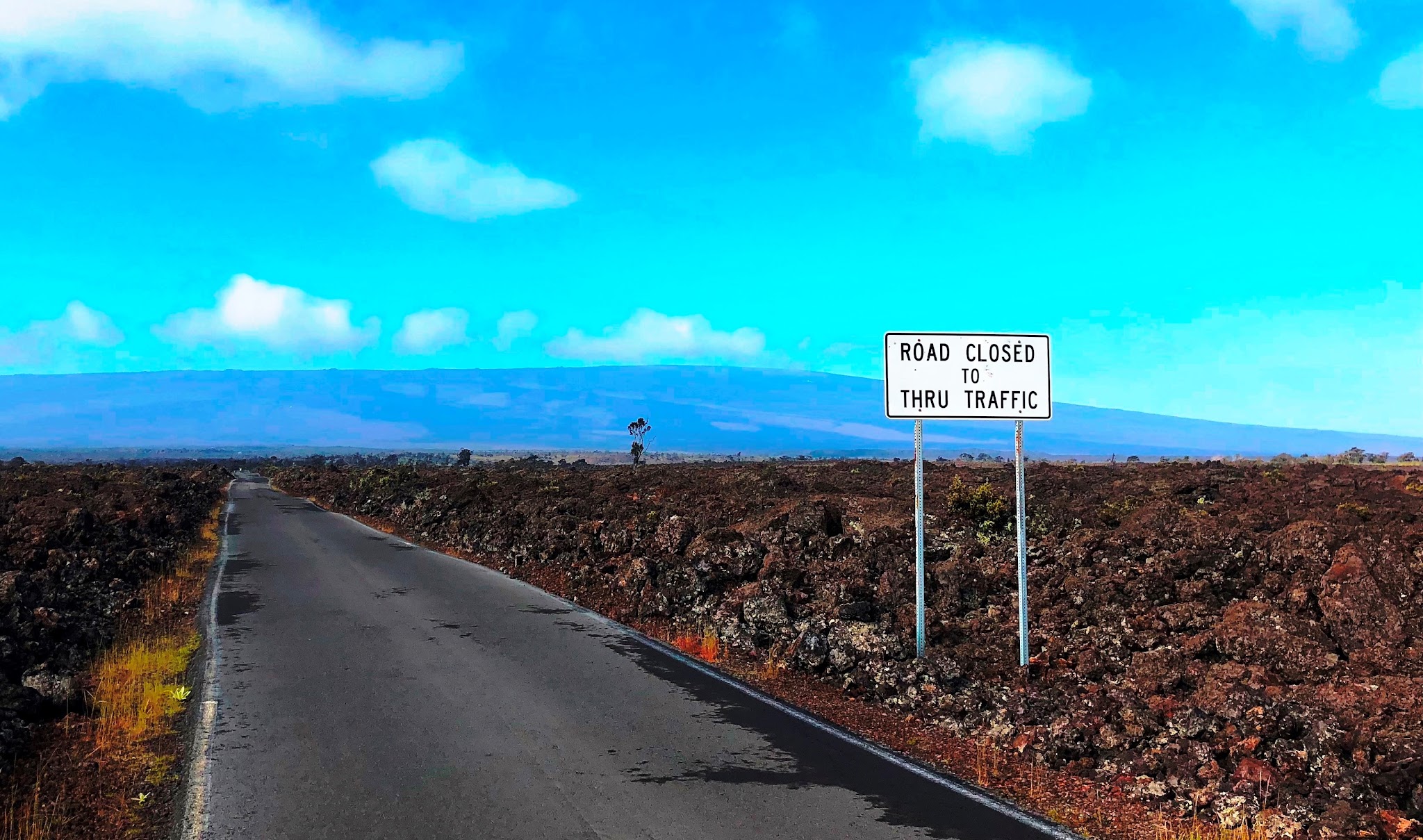 Cycling Mauna Loa Volcano - roadway, lava field and roadway sign