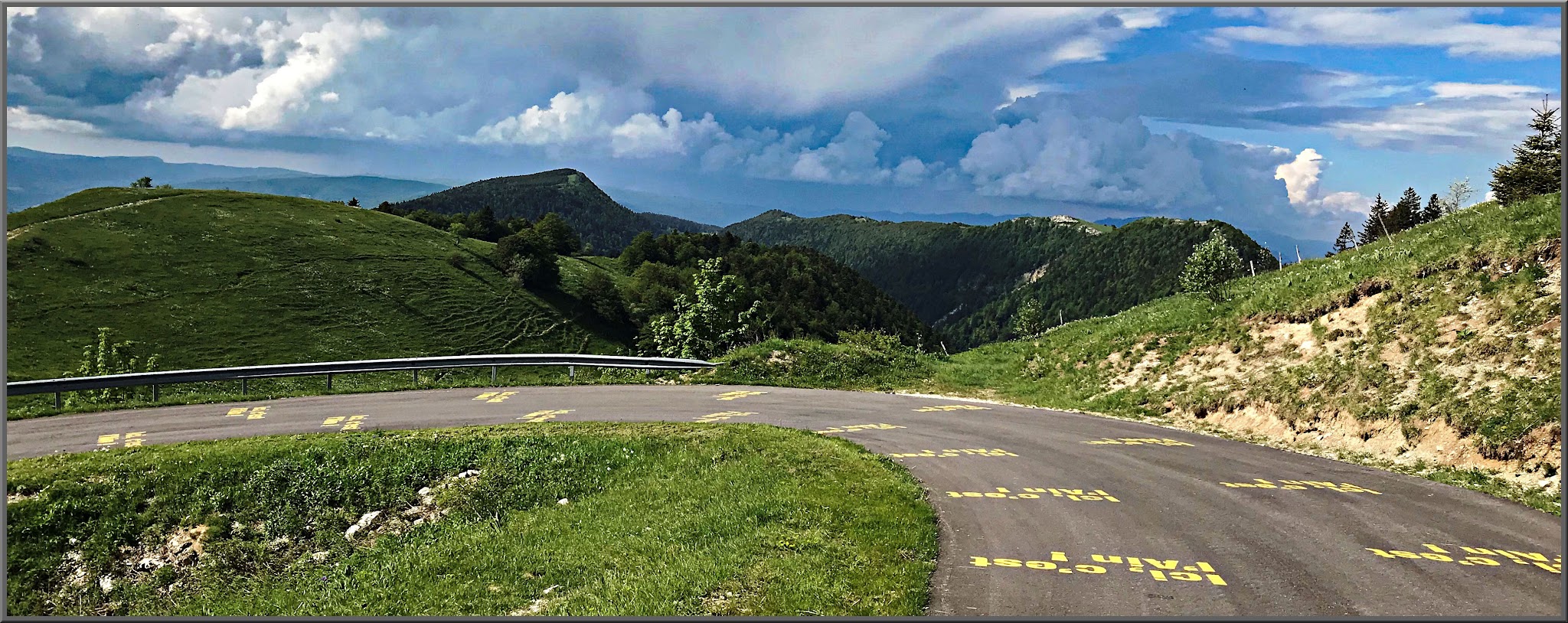 switchback on mountain roadway shows green mountainside views and painted roadway