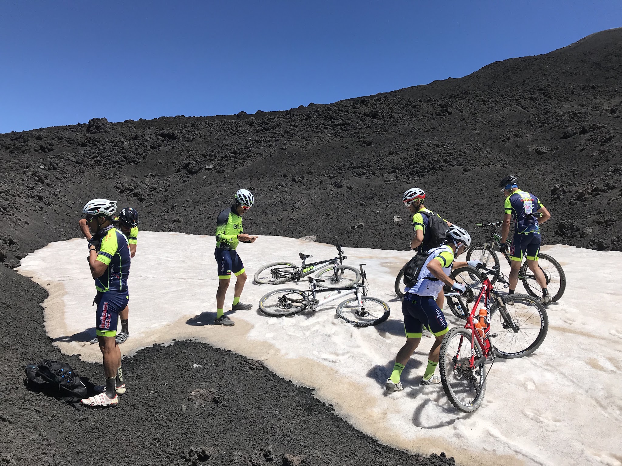 Cyclists in snow with bikes at top of Mount Etna, Sicily, Italy