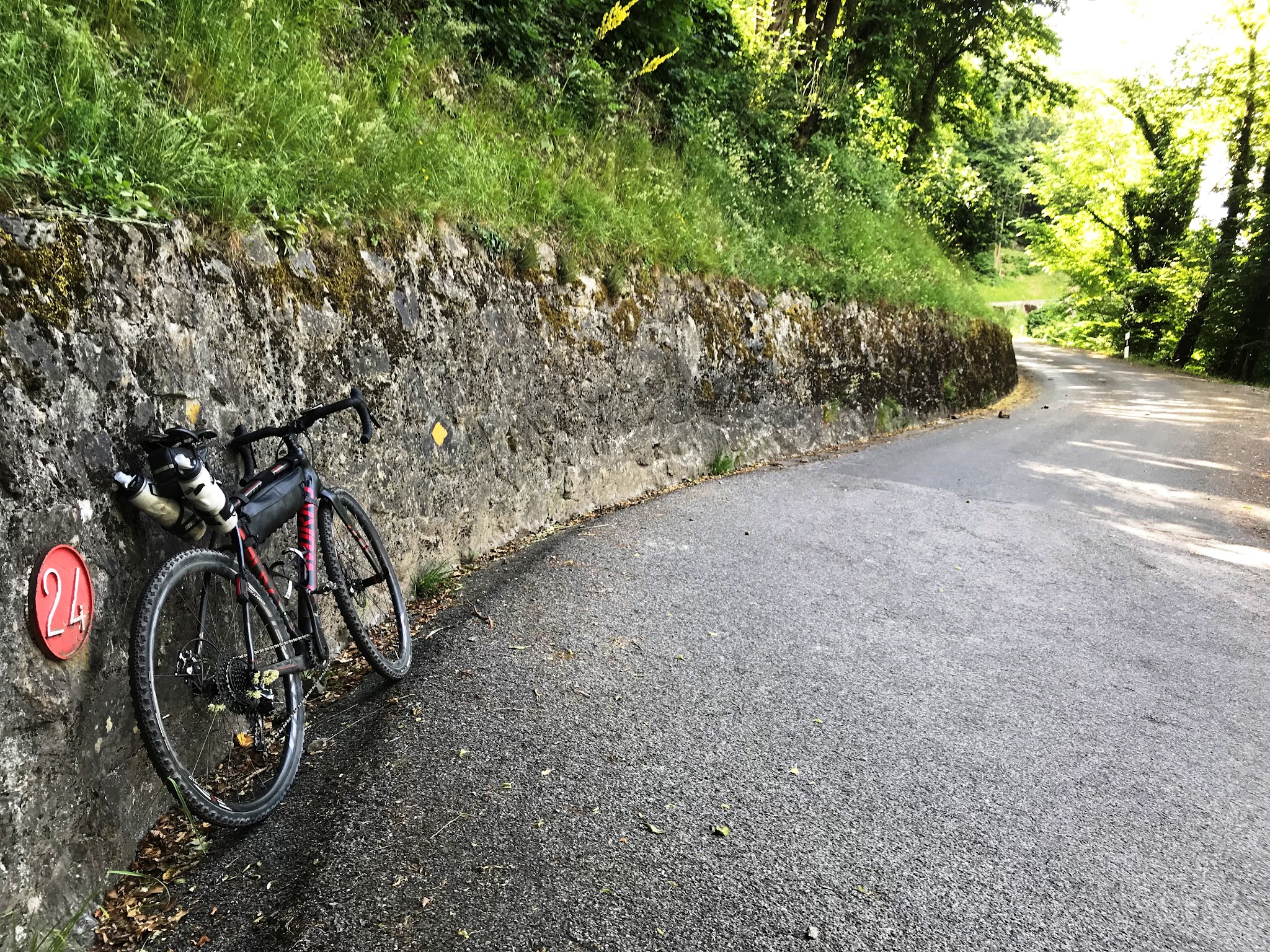 Cycling Rionda - bicycle leaning against wall, hairpin 24 sign and road