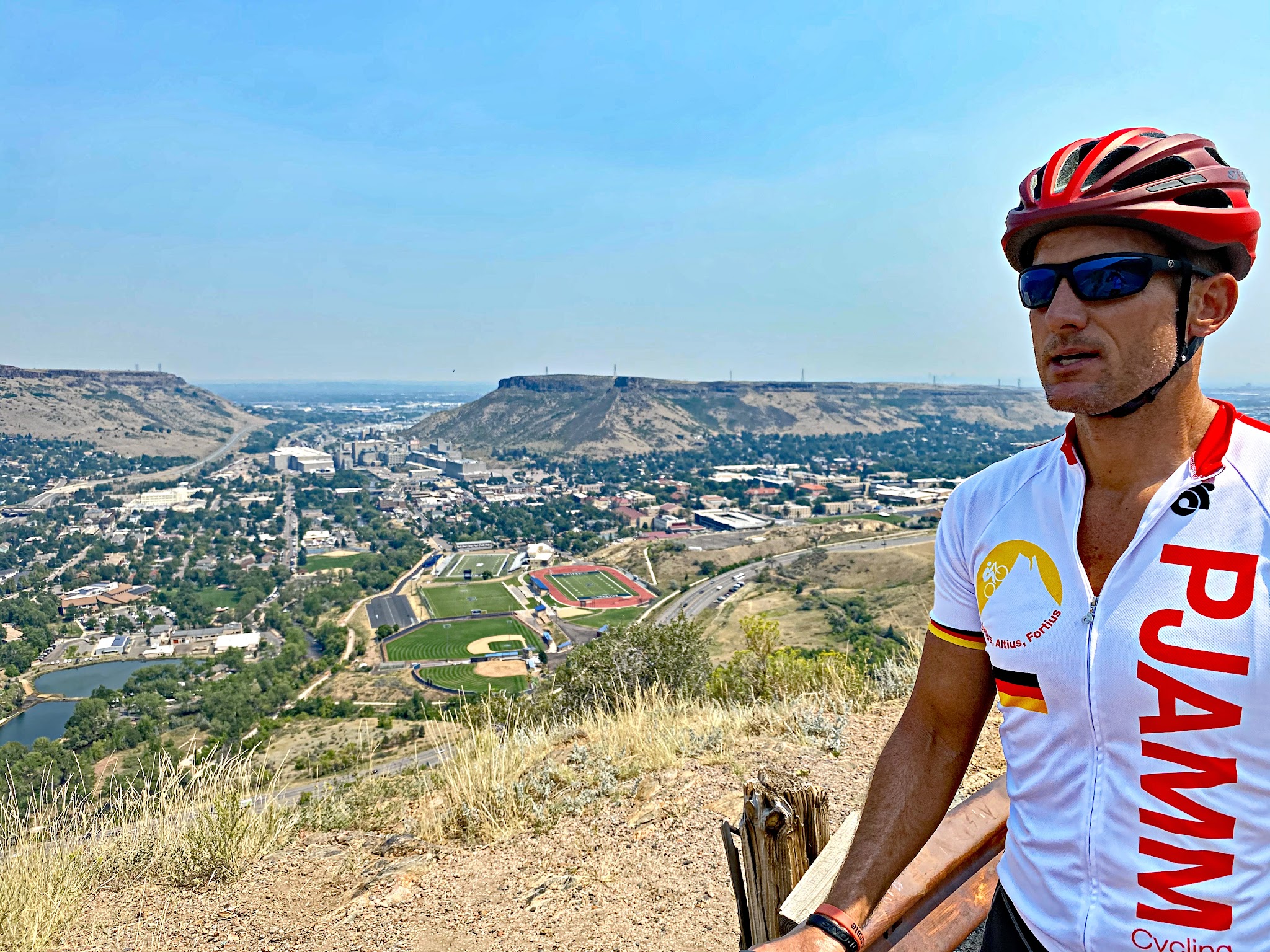 Cycling Lookout Mountain, Colorado - cyclist wearing PJAMM Cycling jersey standing on hillside overlooking Colorado School of Mines