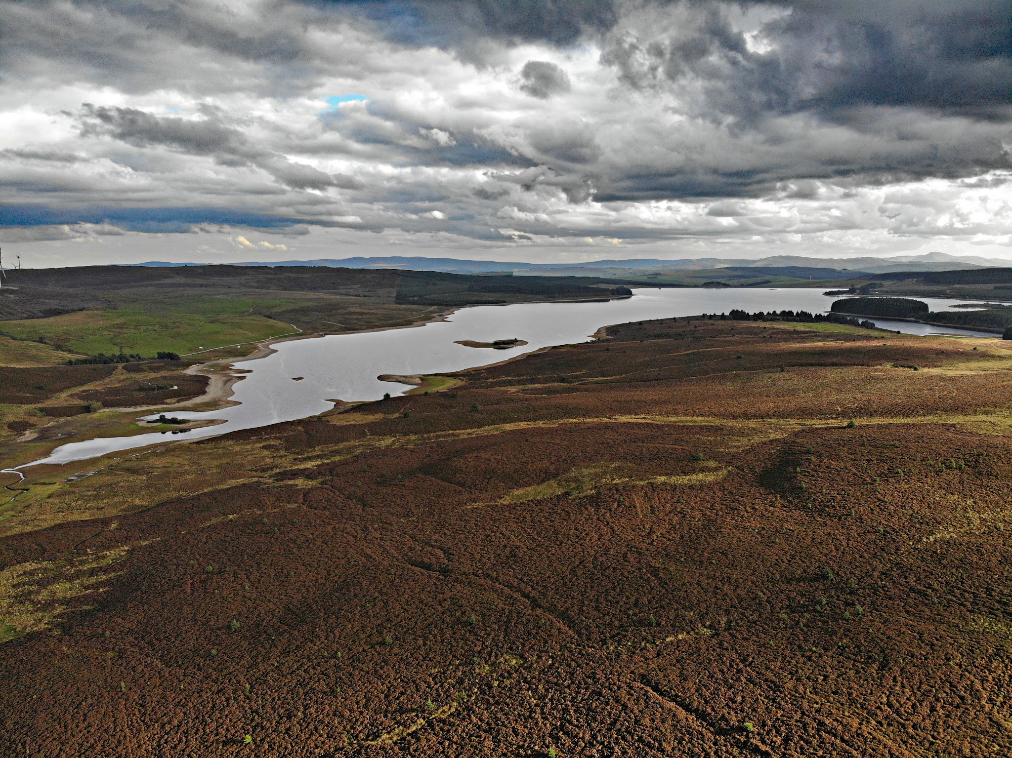 Cycling The Road to Hell, Wales - aerial photo of pastureland with wetland area, grey and white clouds 