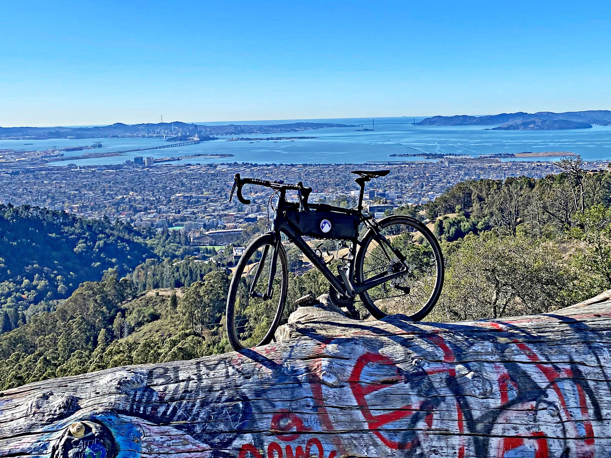 Cycling Tunnel to Grizzly Peak, California - bike parked atop large, graffiti covered fallen log overlooking bay area views
