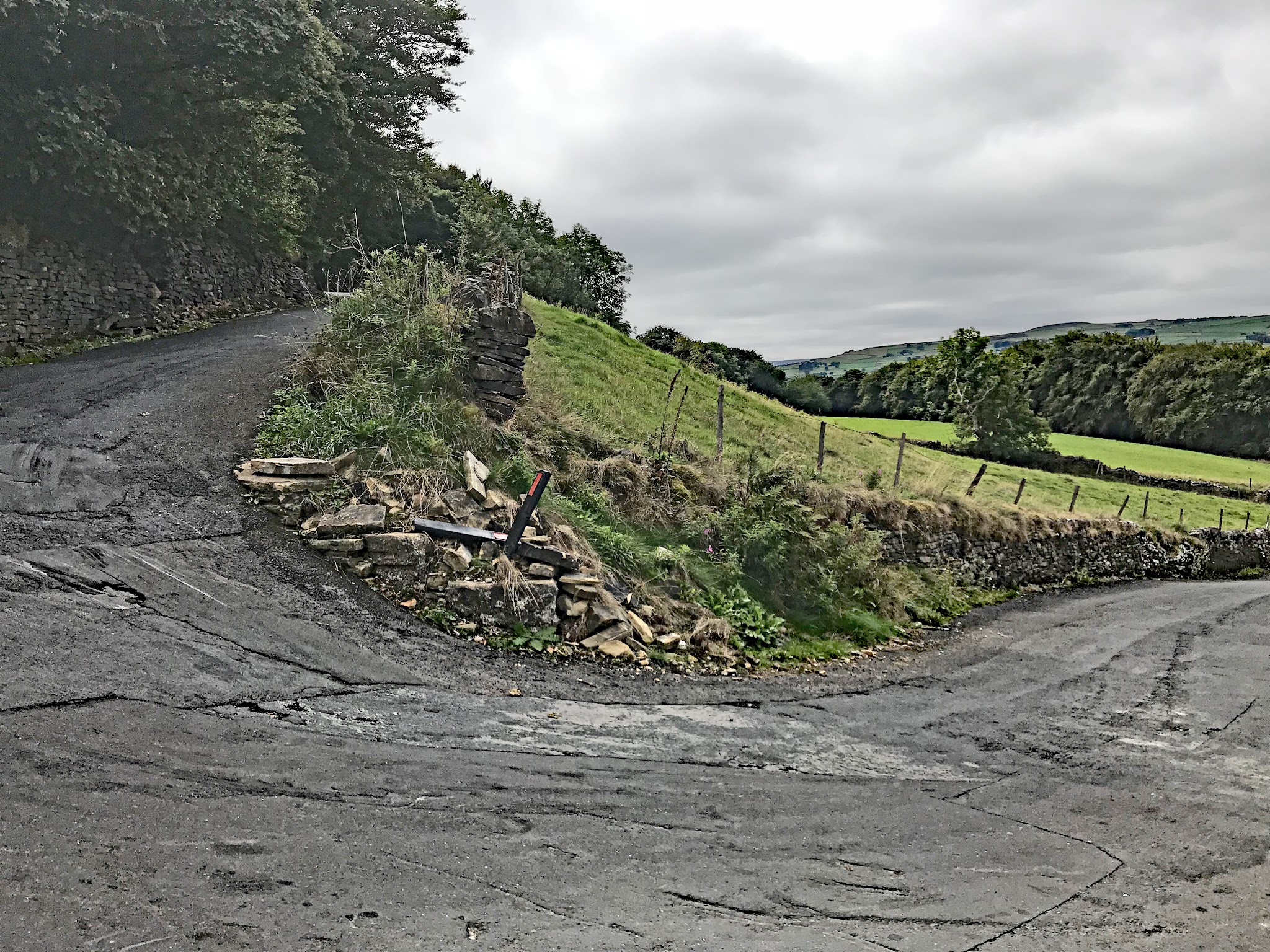 Bike climb Halifax Lane - Simon Warren #44 Greatest Cycling Challenge, Britain  - bike against rock wall with plains behind
