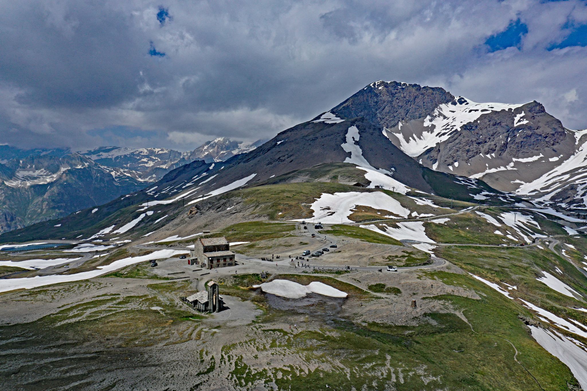 Cycling Col de L'Iseran: aerial drone view of the top of Col de L'Iseran; snow-dotted mountain peak