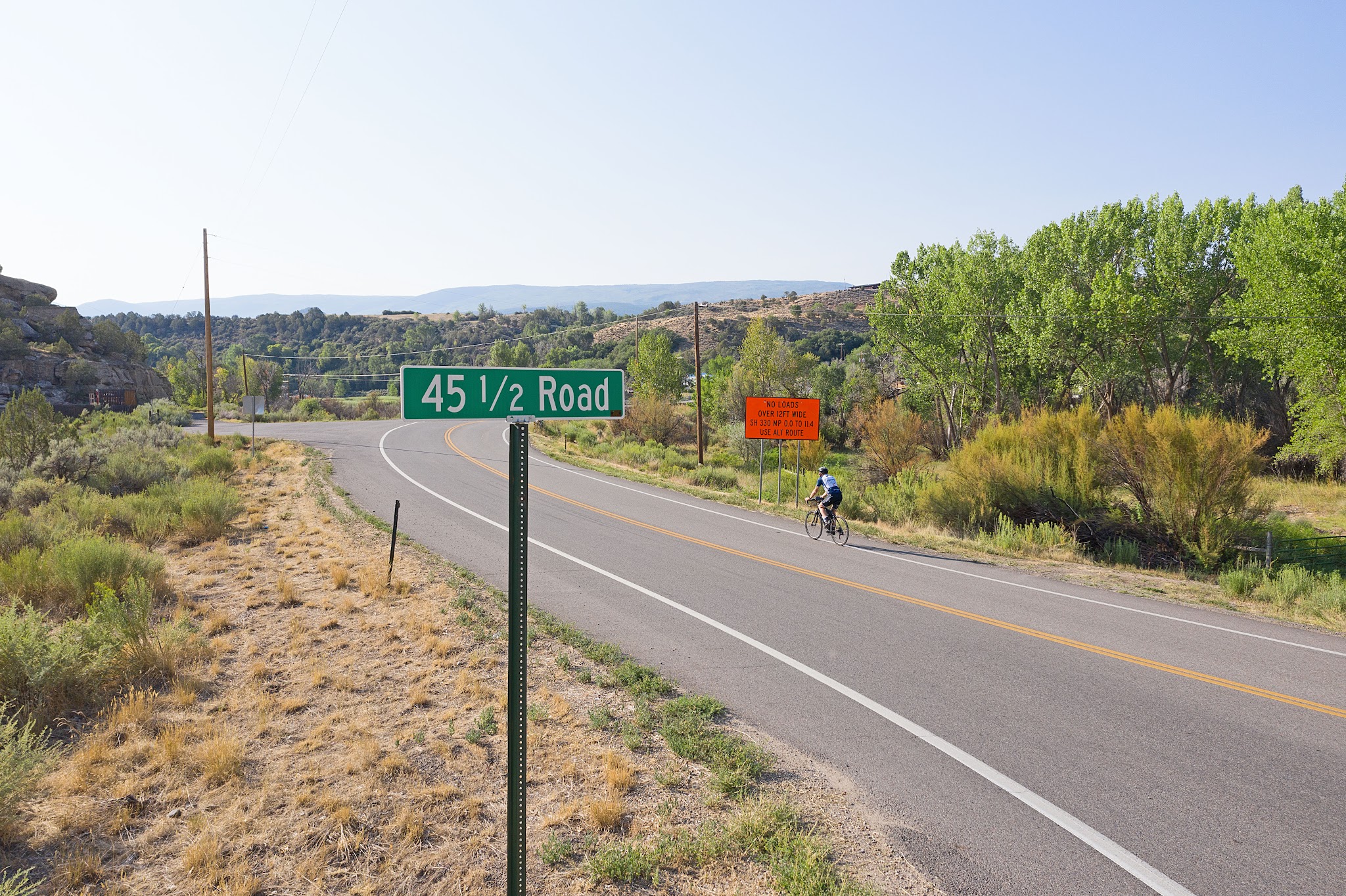 Cycling Grand Mesa North - cyclist riding on roadway near road sign for 45 1/2 Road