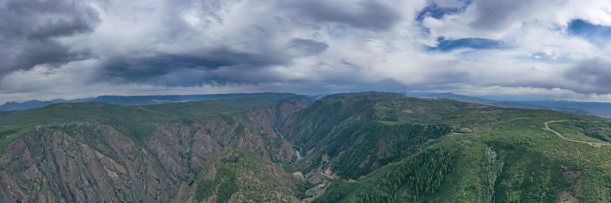 Cycling East Portal, Black Canyon of the Gunnison National Park Cycling East Portal, Black Canyon of the Gunnison National Park - panoramic view overlooking mountain tops and large valley between them, large white clouds above