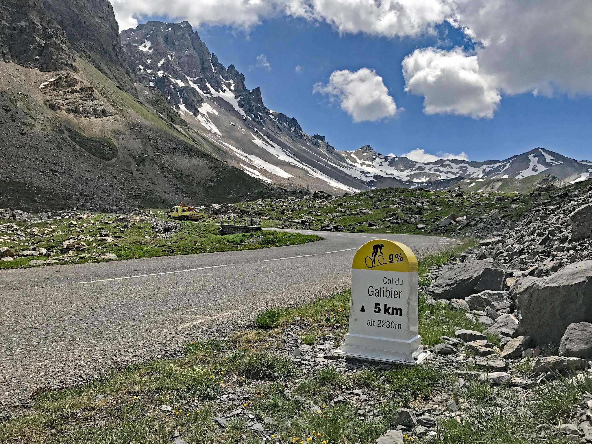 Climbing by bike The World's most gorgeous bike climbs - Col du Galibier - cyclist riding by kilometer marker - mountains with snow in background