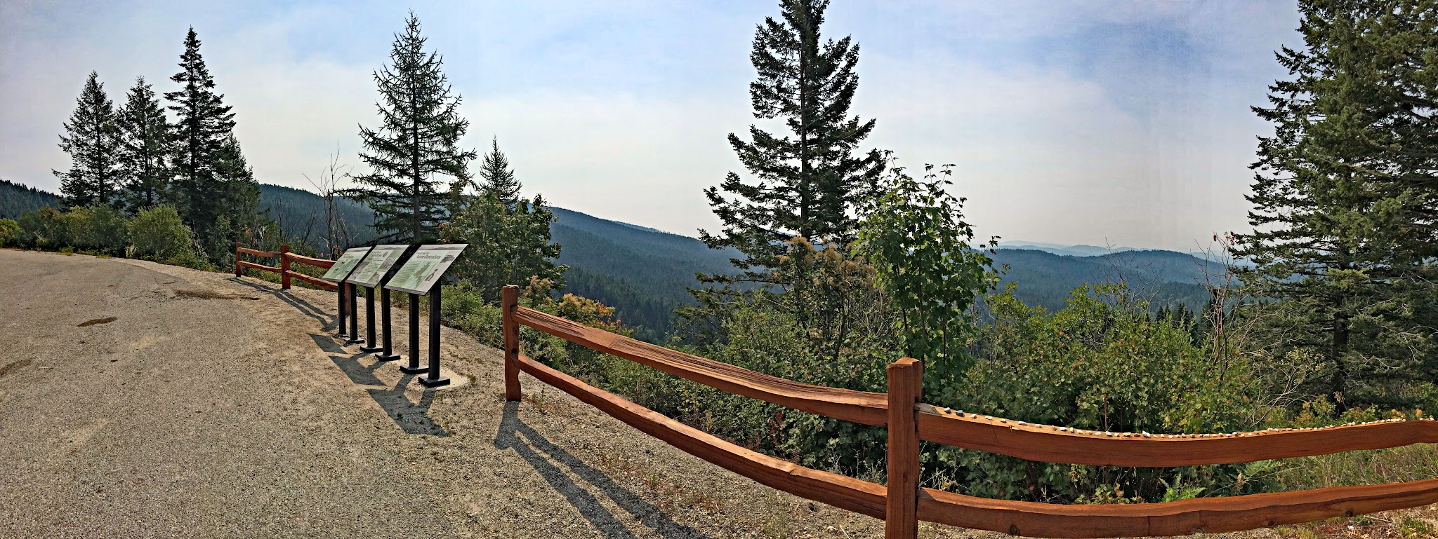 Cycling Mt. Spokane, Washington - lookout viewpoint along roadway, informational signs looking down upon mountain range and evergreen trees