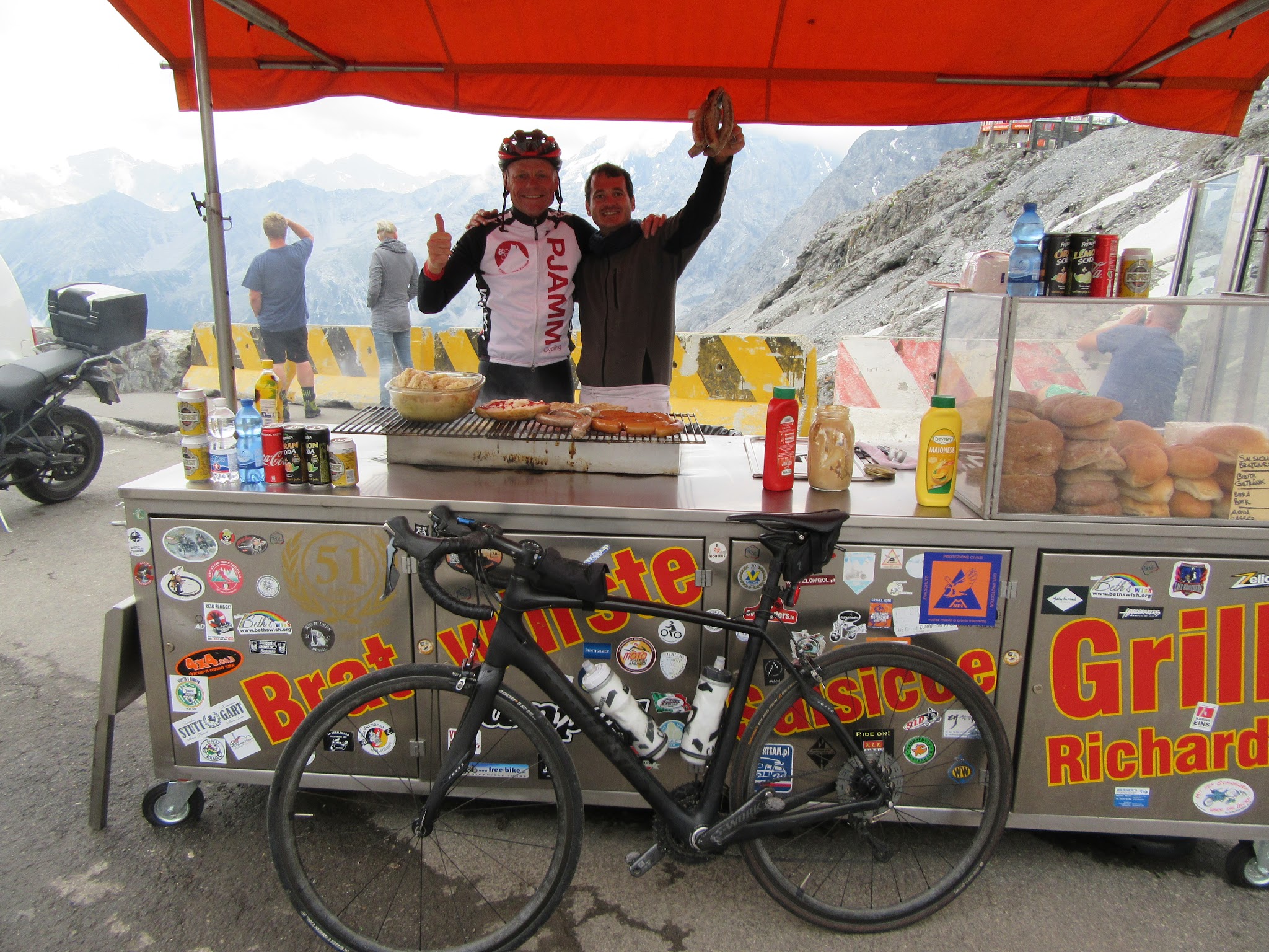 Umbrail Pass bike climb - bratwurst and food cart at passo dello stelvio with cyclist, bike and cook