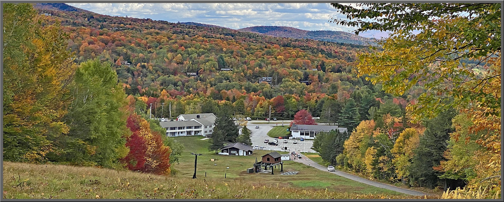 Cycling Mt. Mansfield, Vermont - looking down hillside toward town, hills covered in bright fall foliage