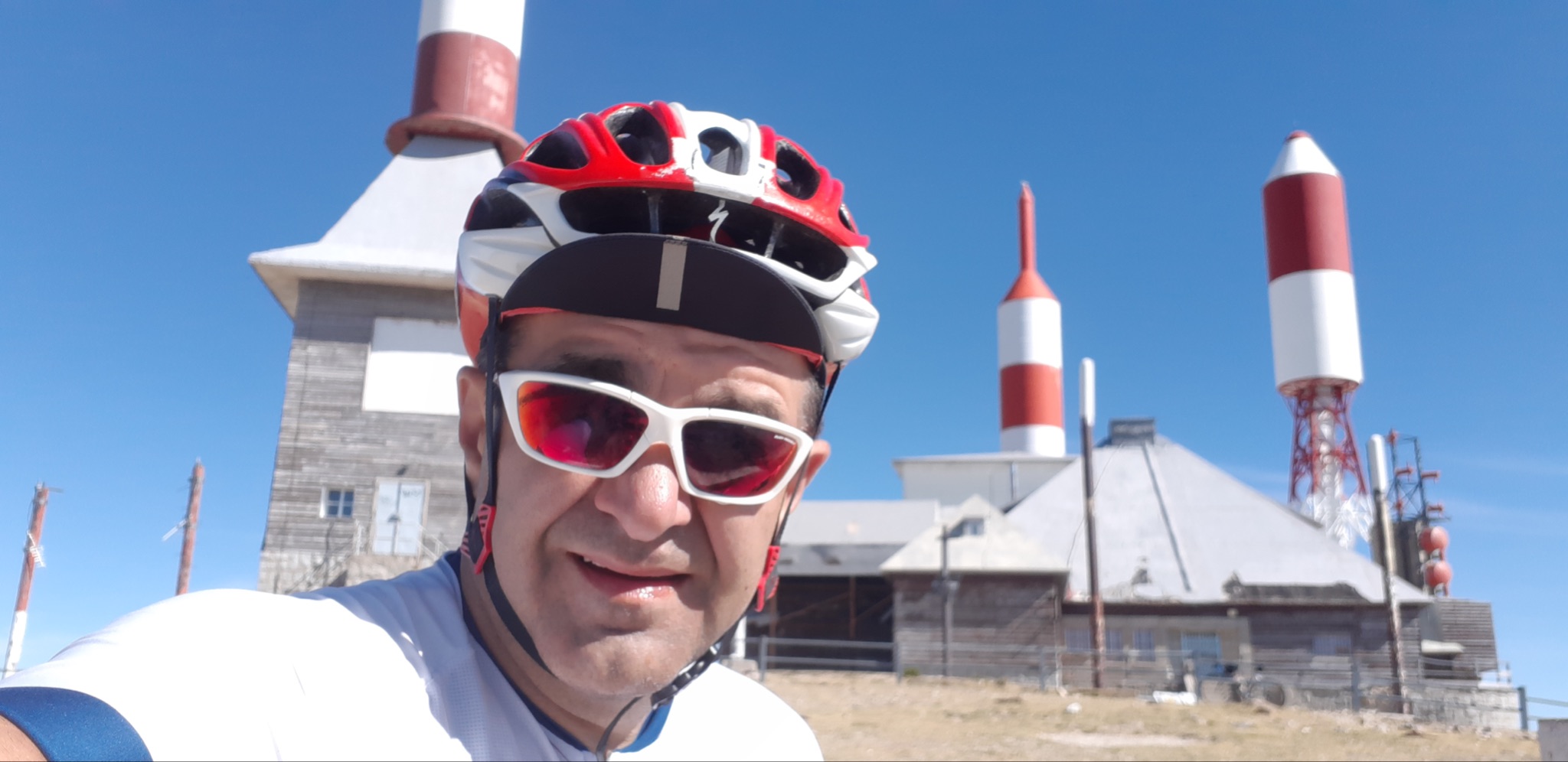 Cycling Bola del Mundo vía Puerto Navacerrada, Spain - selfie of cyclist Jose standing in front of antennas at climb's summit