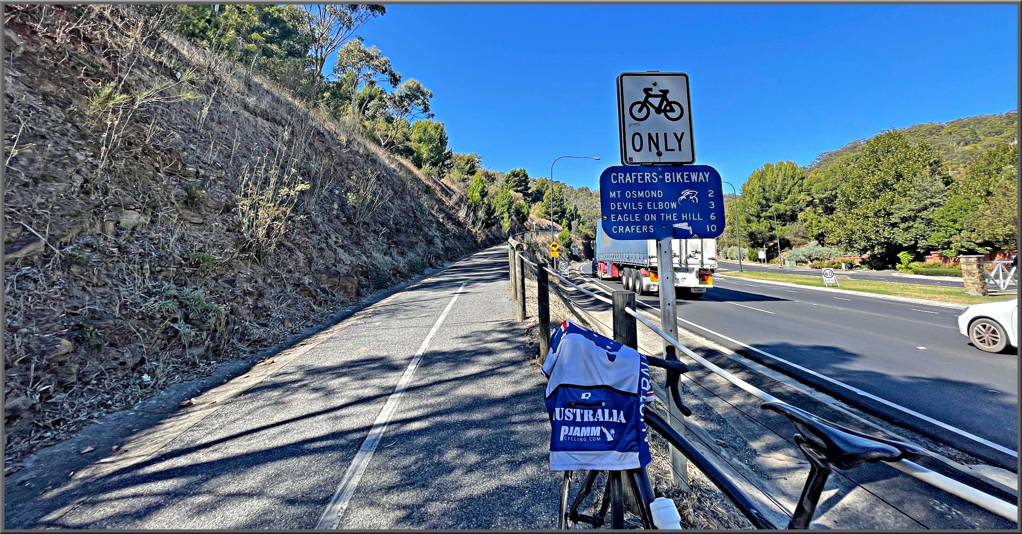 bike with PJAMM Cycling Australia jersey draped over it leaning against roadsign for Crafers Bikeway