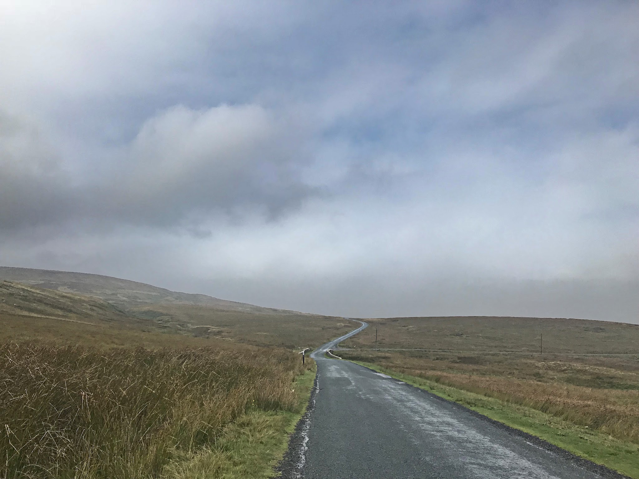 Cycling Tan Hill, UK - very narrow, very long, gently curved road stretching as far as the eye can see through wide open pastureland 