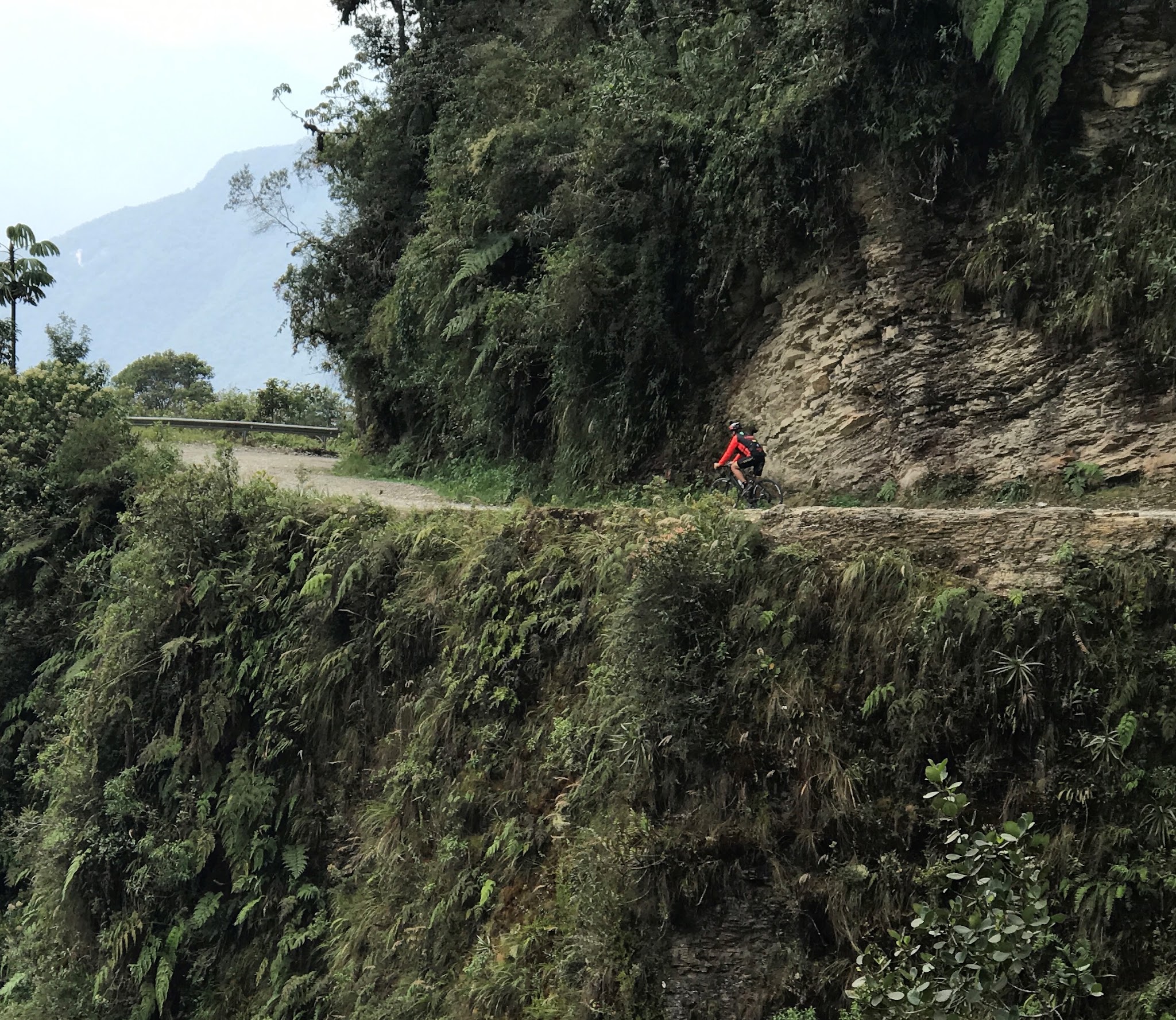 Bicyclist riding along narrow road with cliff on Death Road