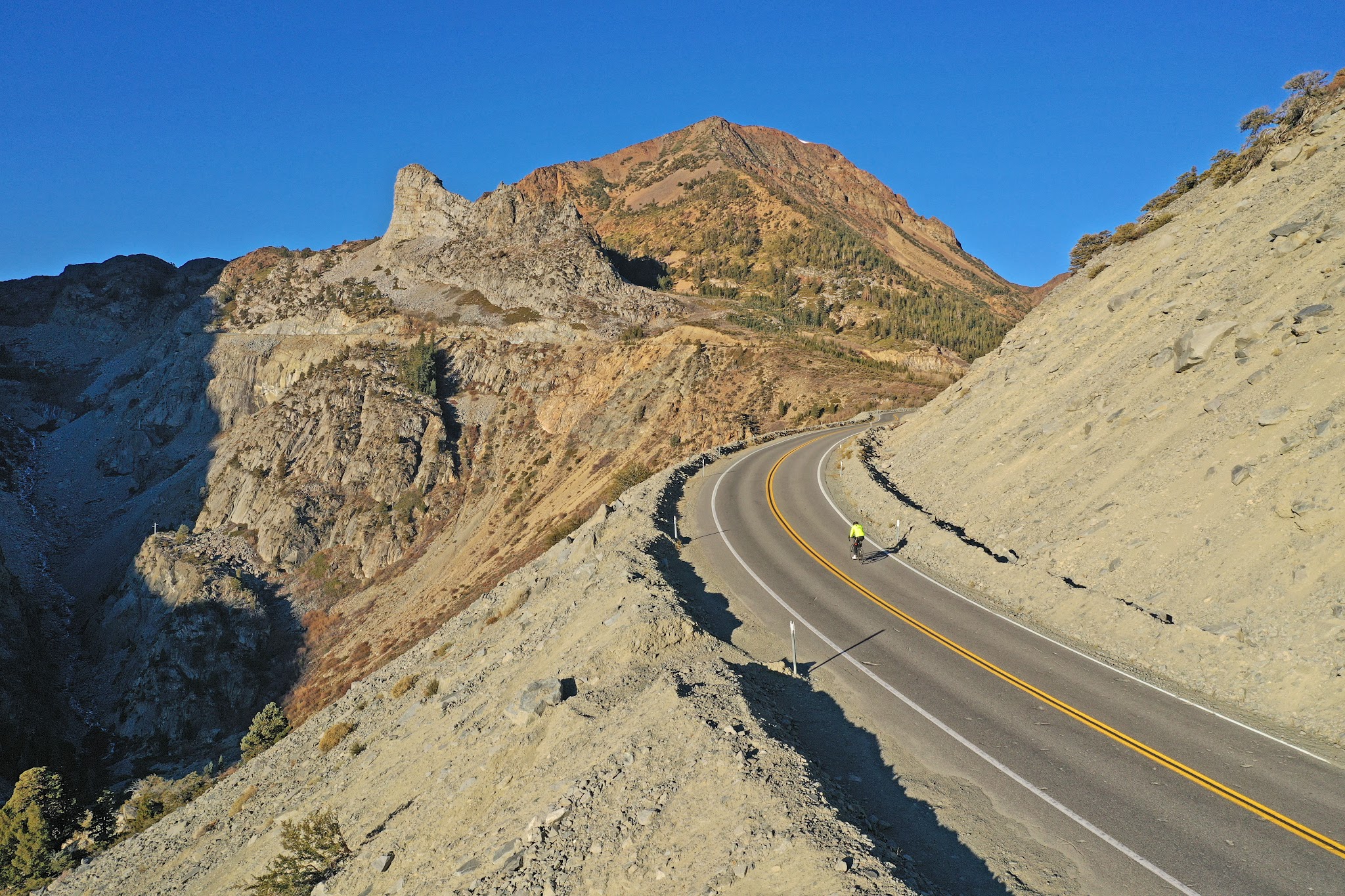 Aerial drone view of cyclist on two-lane roadway climbing up Tioga Pass 